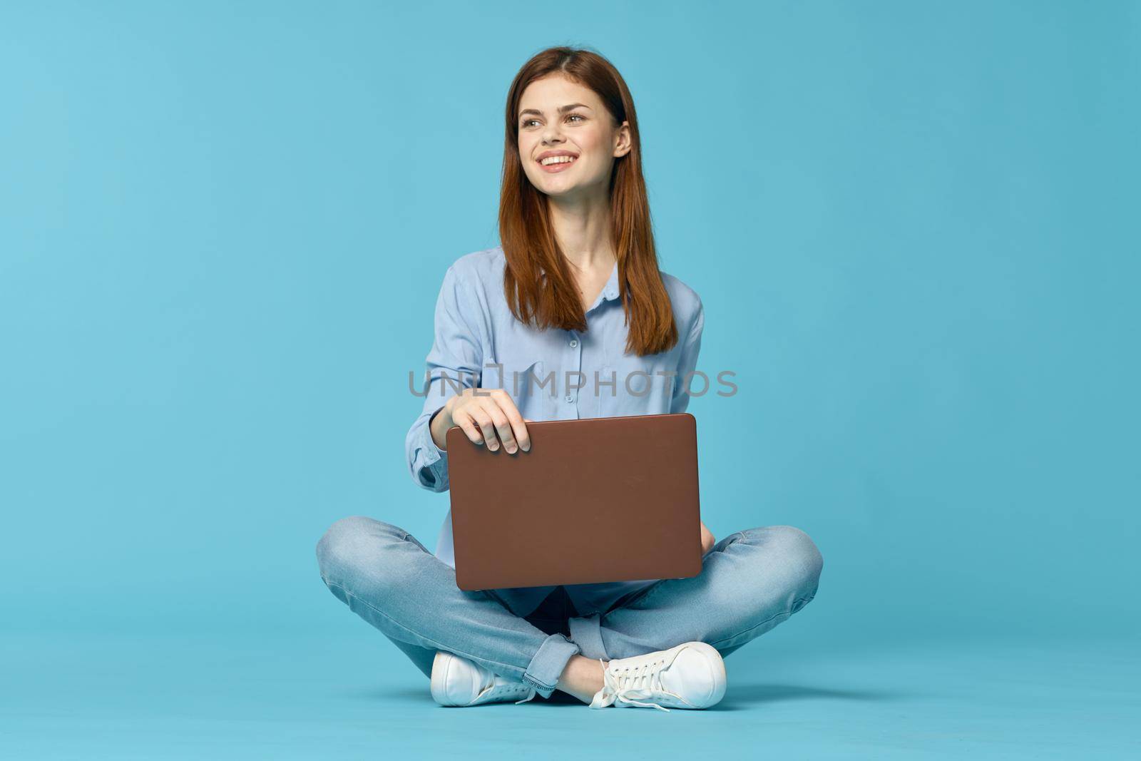 woman with laptop learning internet online education blue background. High quality photo