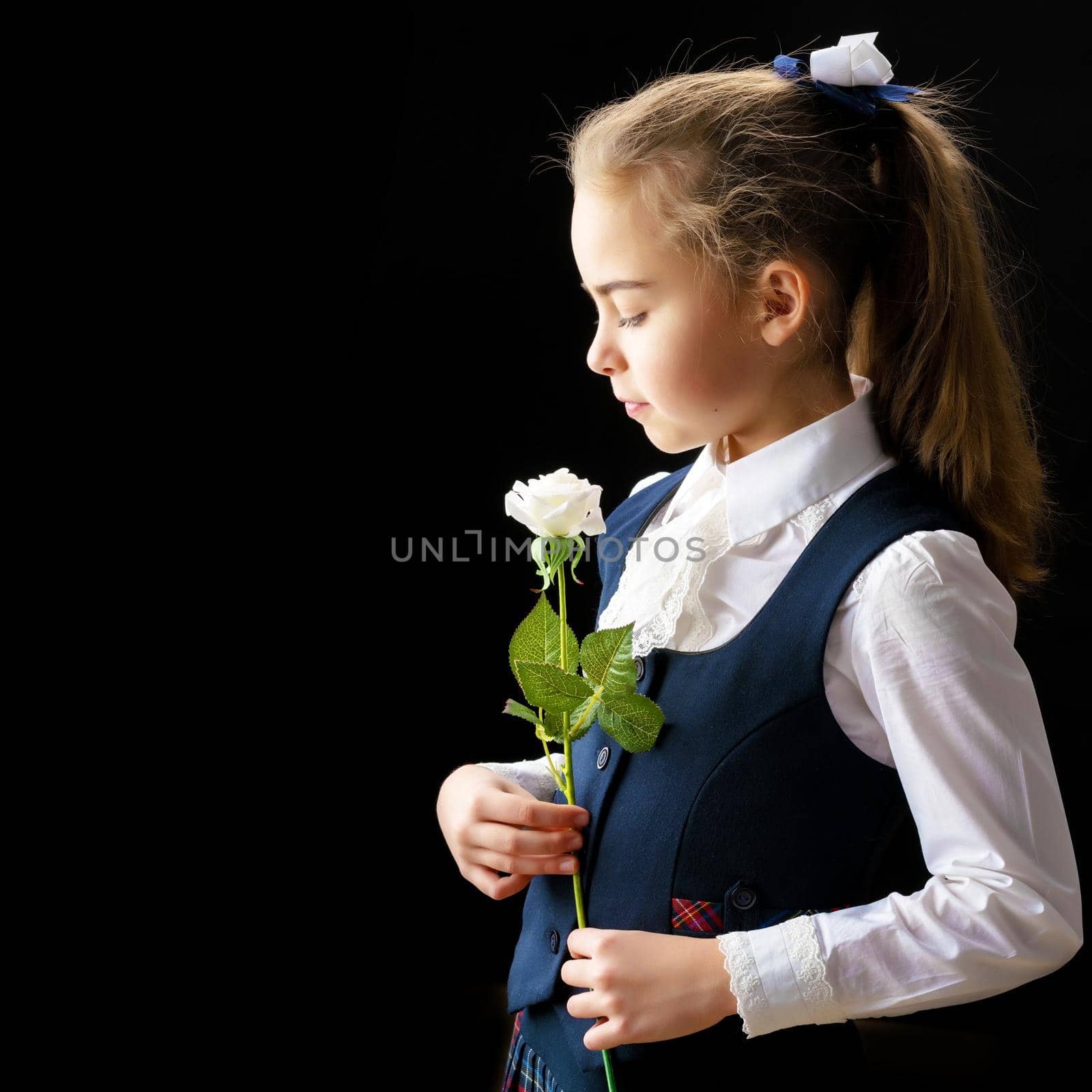 Beautiful little girl with a flower in her hand. The concept of style and fashion. On a black background.