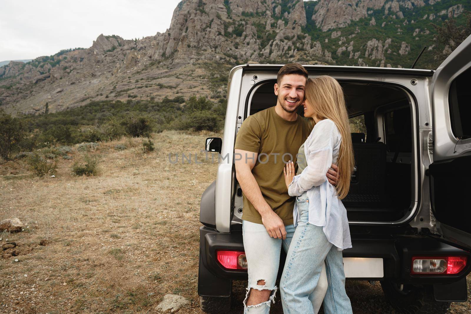 Young happy couple on a road trip sitting in car trunk outdoor