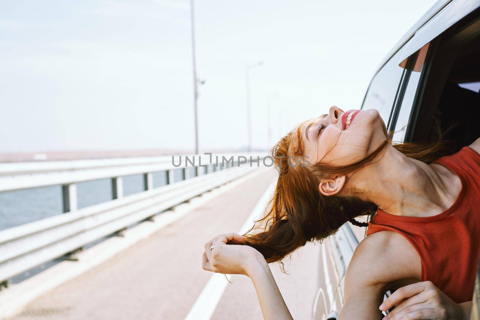 cheerful woman peeking out of the car window trip road travel. High quality photo