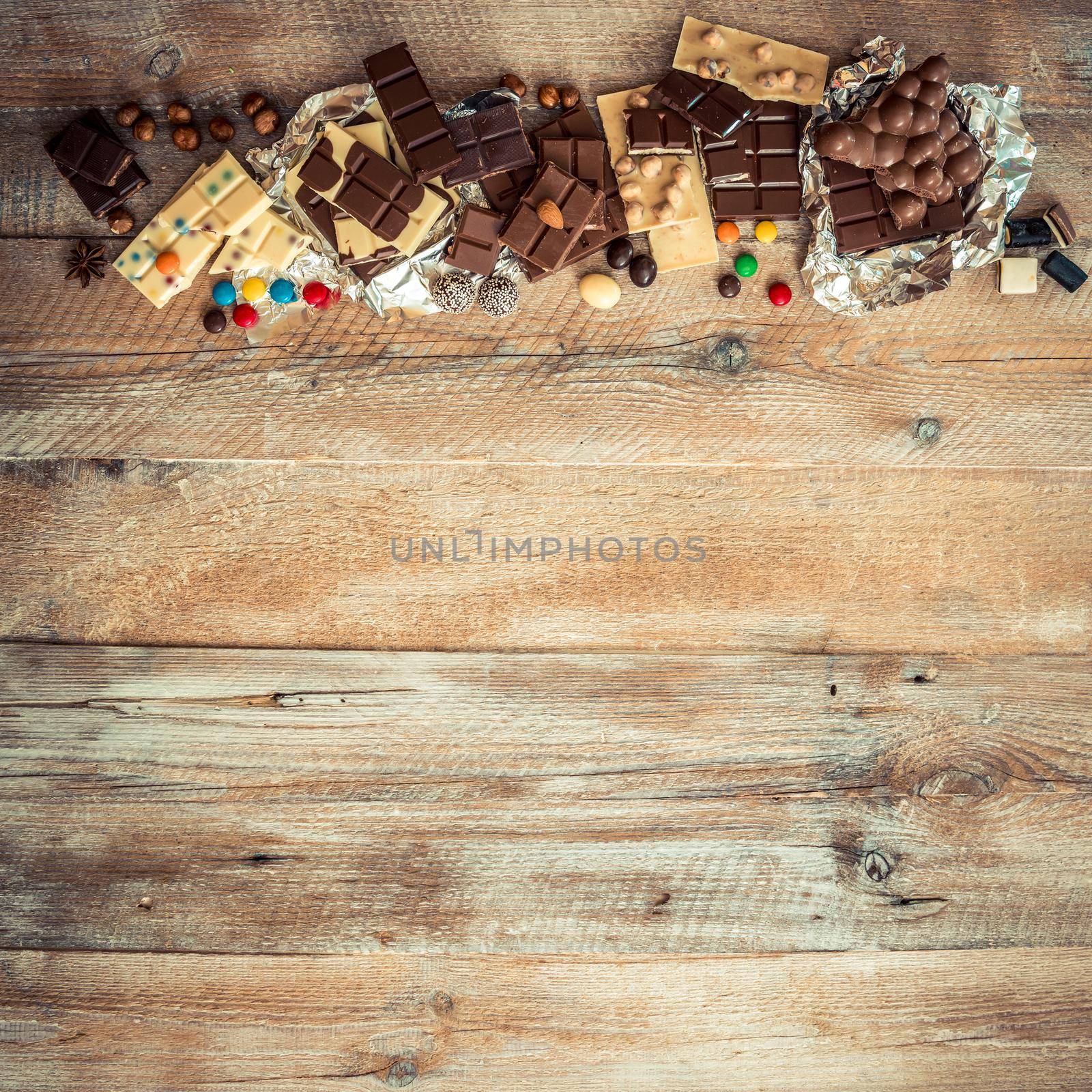 chocolate and candies on a wooden background with space for text