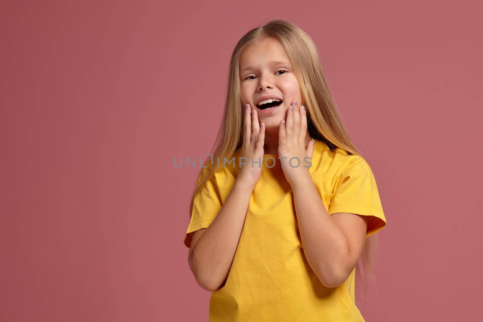little girl in a yellow T-shirt on a coral background. looking shyly