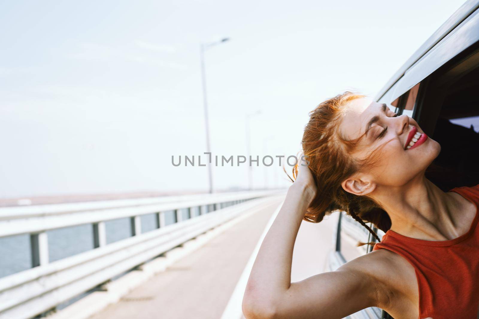 cheerful woman peeking out of the car window trip road travel. High quality photo