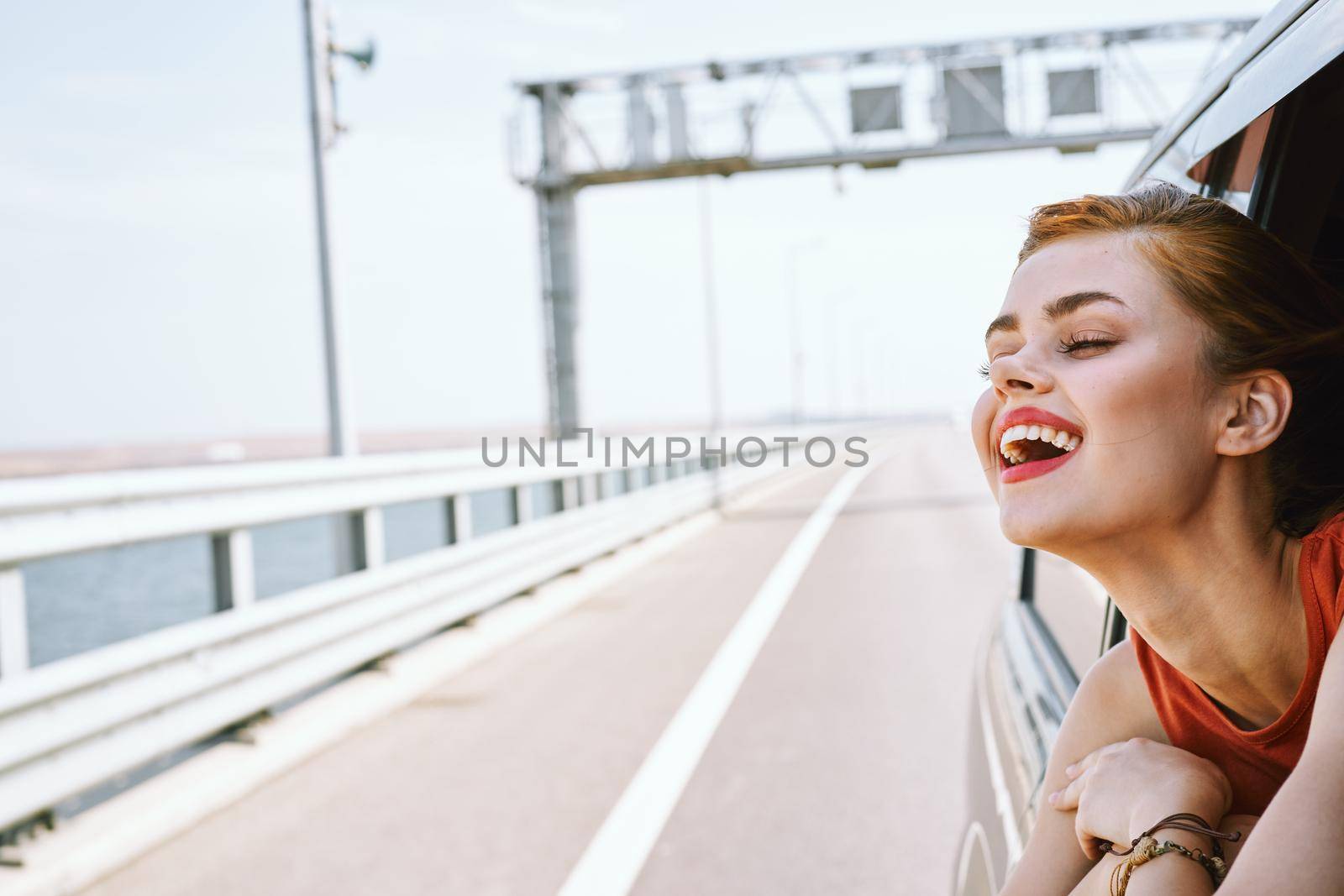 cheerful woman peeking out of the car window trip road travel. High quality photo