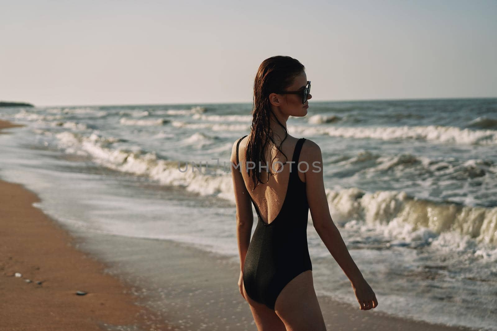 cheerful woman in black swimsuit sunglasses beach walk travel. High quality photo