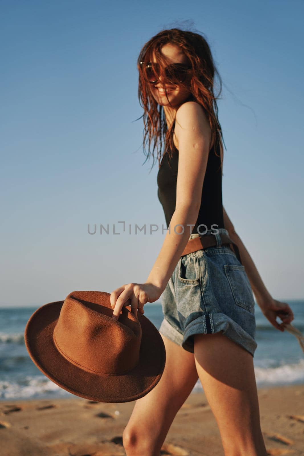 cheerful woman in a hat with sunglasses walking with a bag. High quality photo