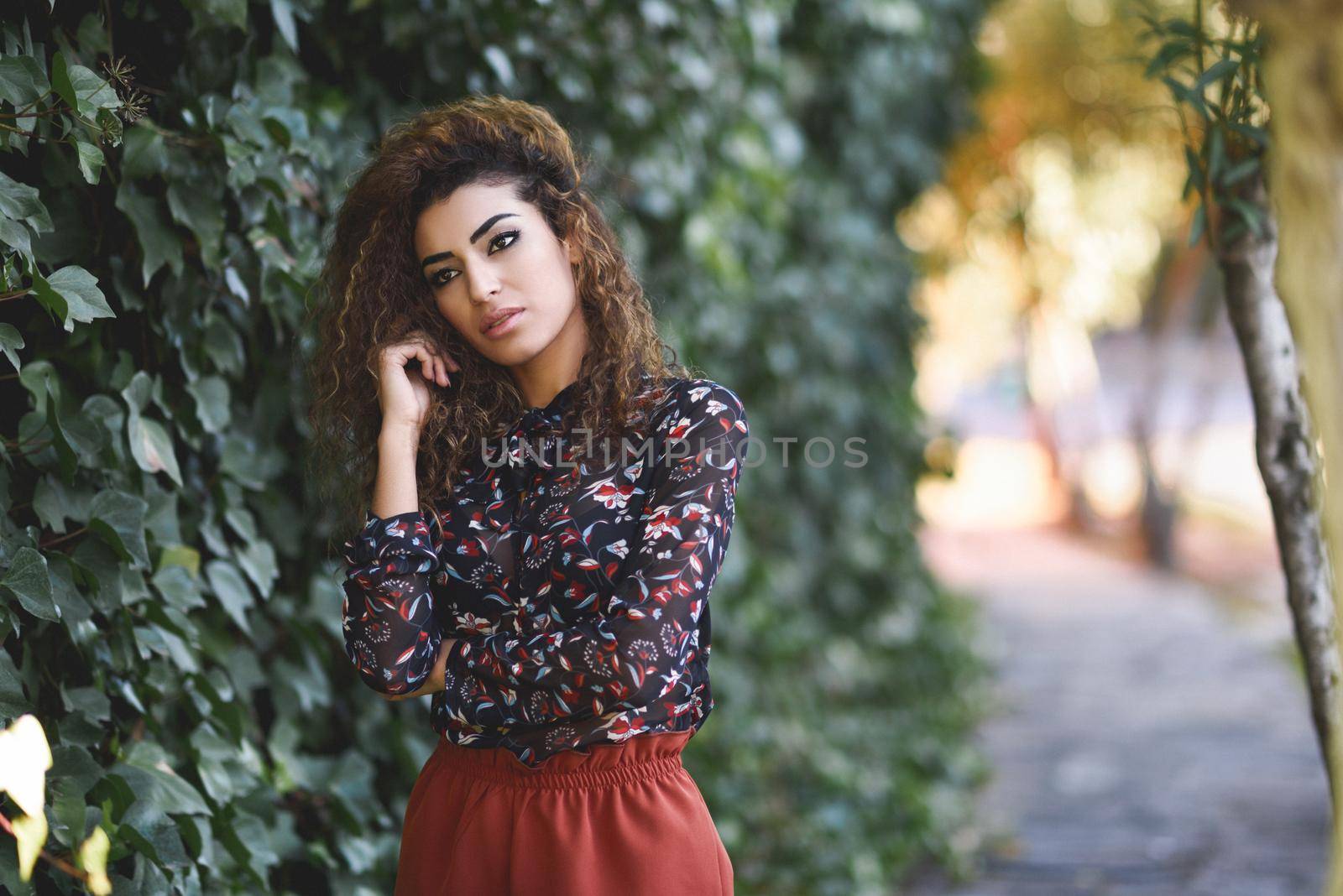 Beautiful young arabic woman with black curly hairstyle. Arab girl wearing casual clothes in the street.