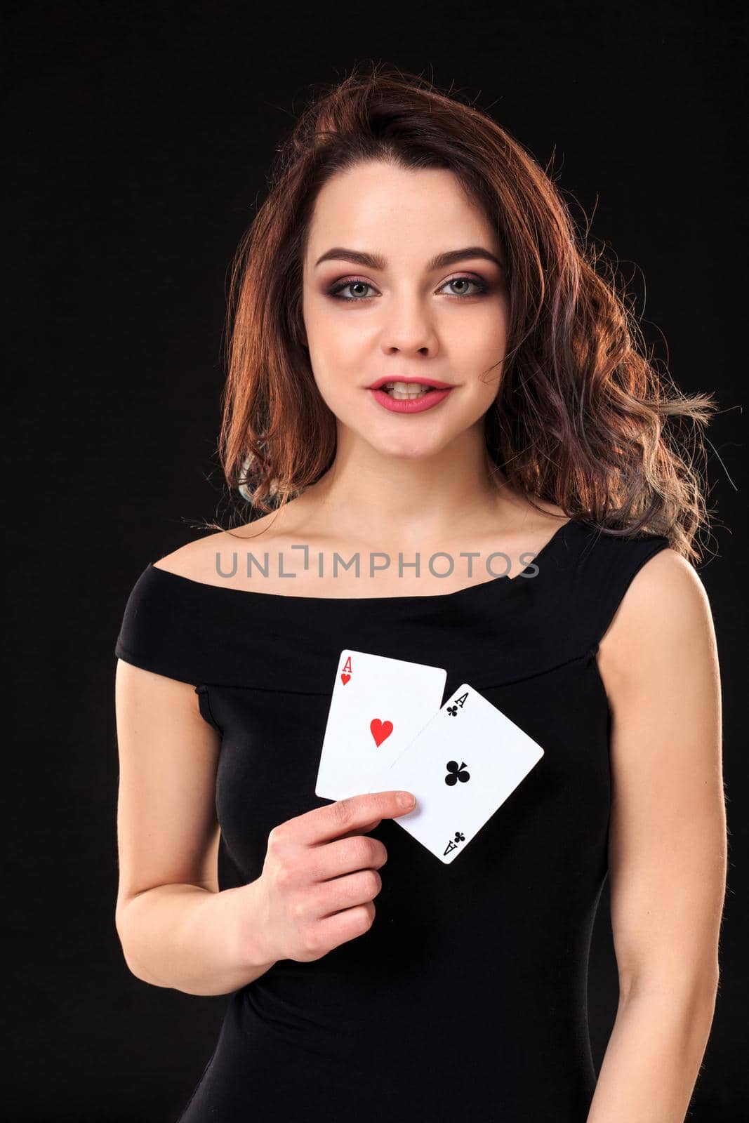 Young woman holding playing cards against a black background. Gambling. Poker. Two Aces.