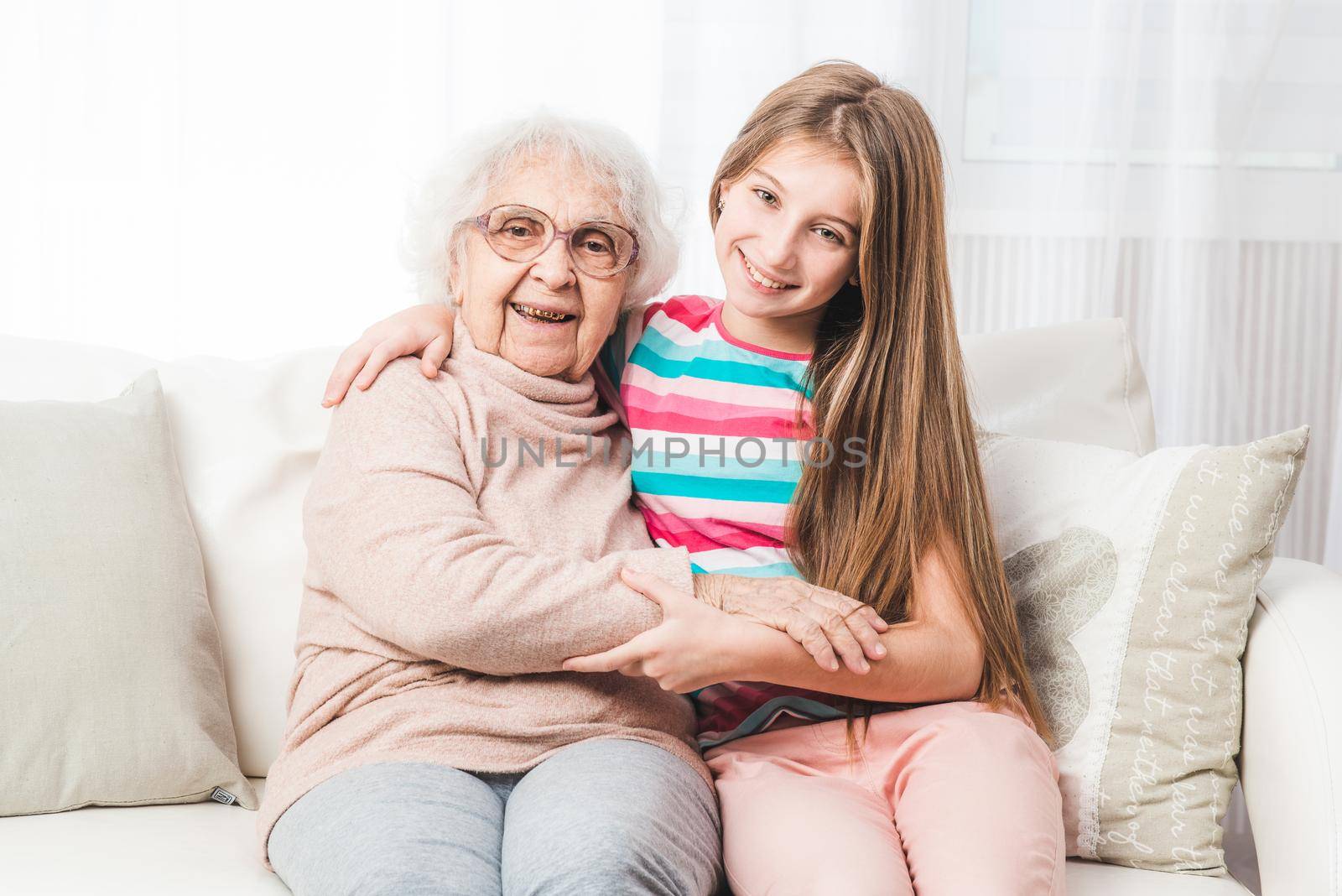 Smiling granddaughter sit hugging with grandmother