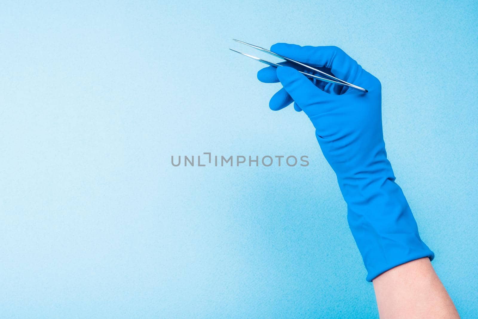 Hand in blue glove holding dental tweezers by GekaSkr