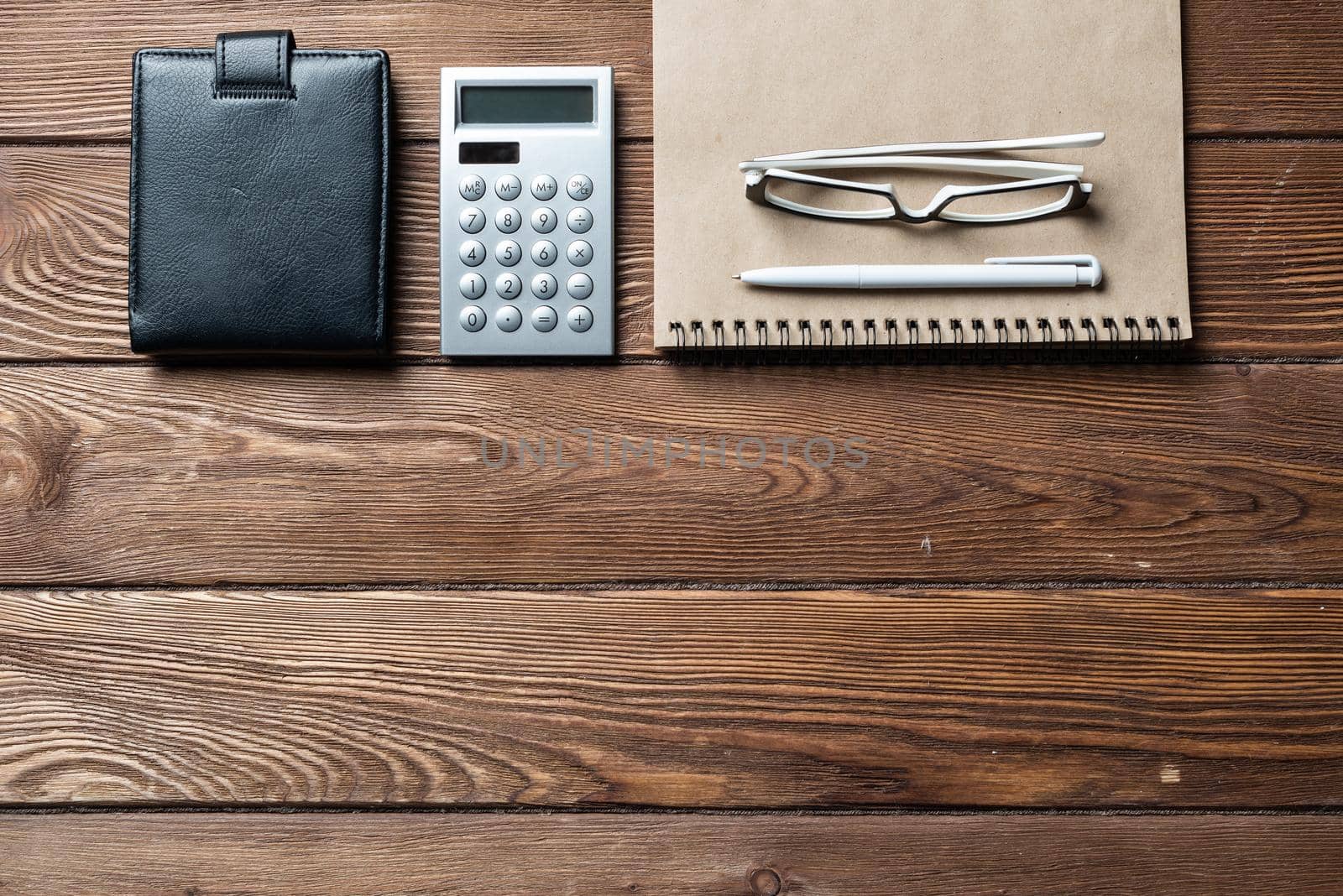 Still life of accountant workspace with office accessories. Flat lay old hardwood desk with black leather wallet, calculator and notepad. Accounting and banking services. Finance and payment concept