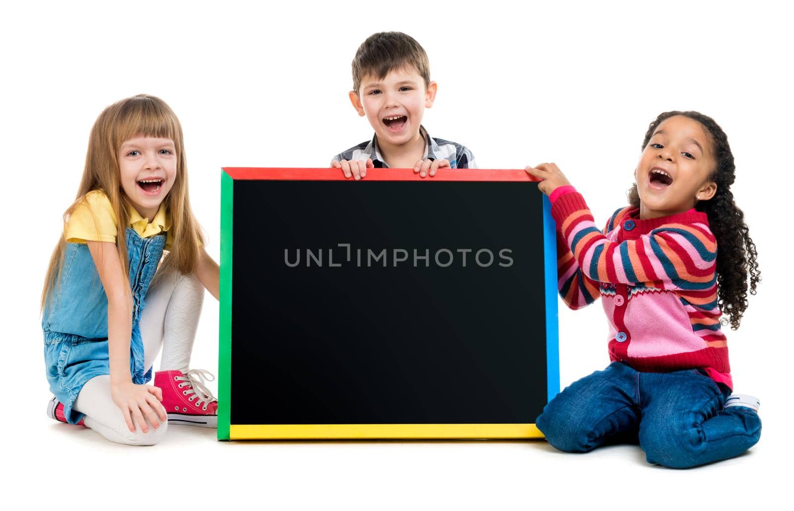 tree cheildren look at little blackboard sitting on the floor isolated on white background