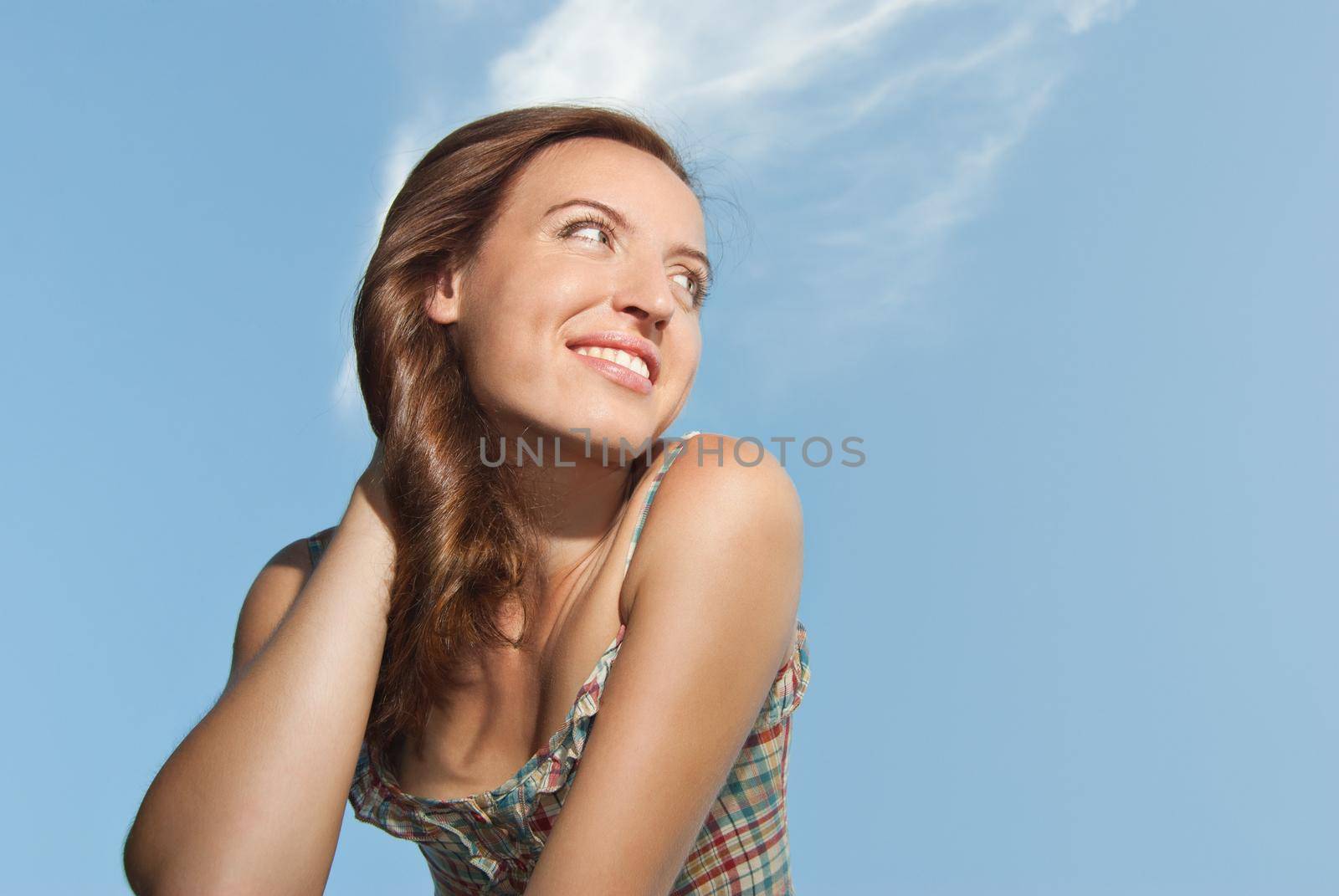 Beautiful young woman smiling against the sky by Julenochek