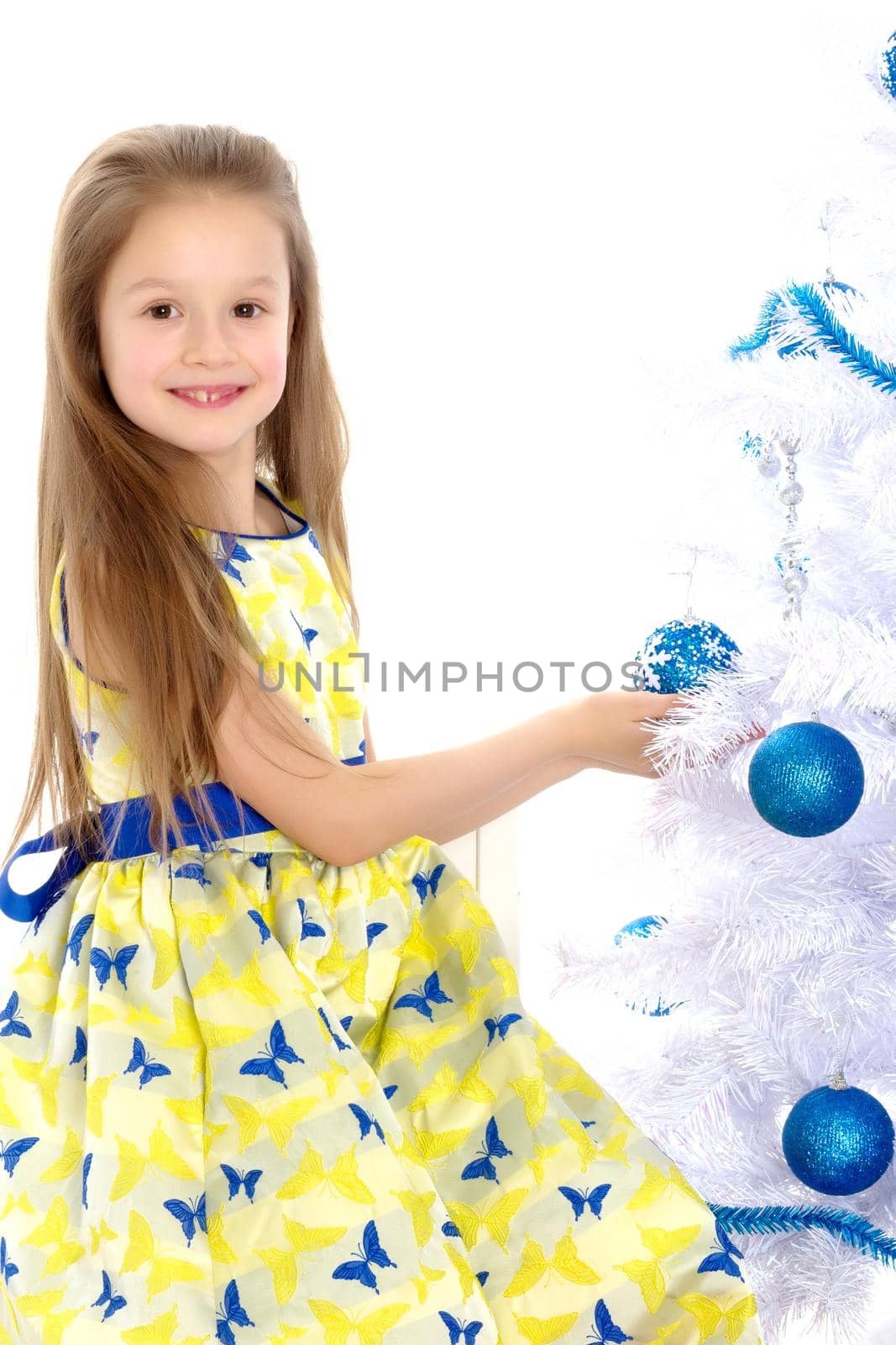 A happy little girl is decorating a Christmas tree. The concept of holidays, Christmas and New Year. Isolated on white background.