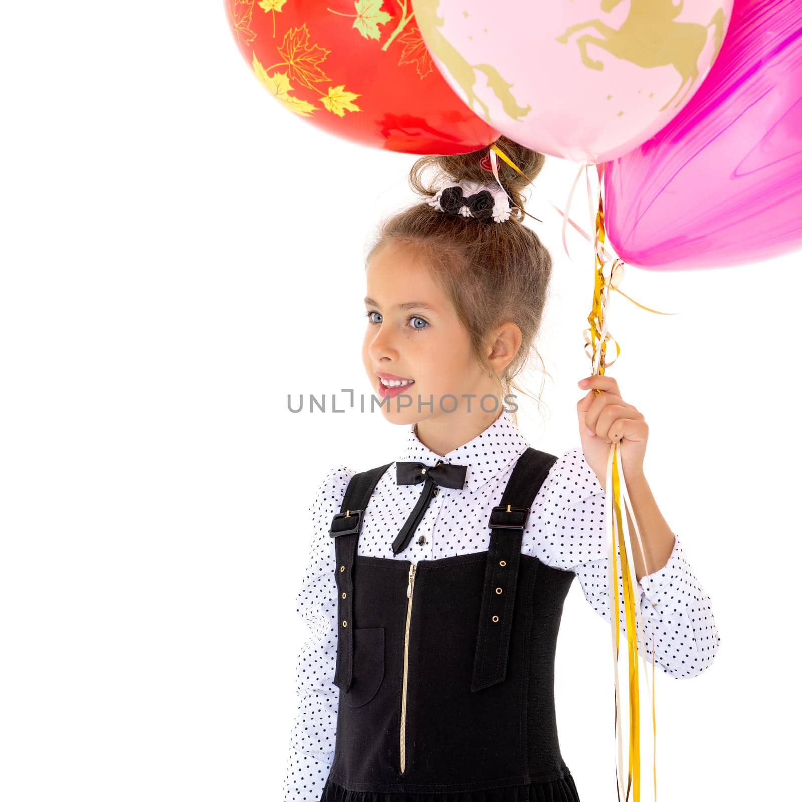Colorful photo, beautiful girl holding bunch of balloons on white background. The girl is smiling and looking at the camera. Holiday concept, happy childhood.