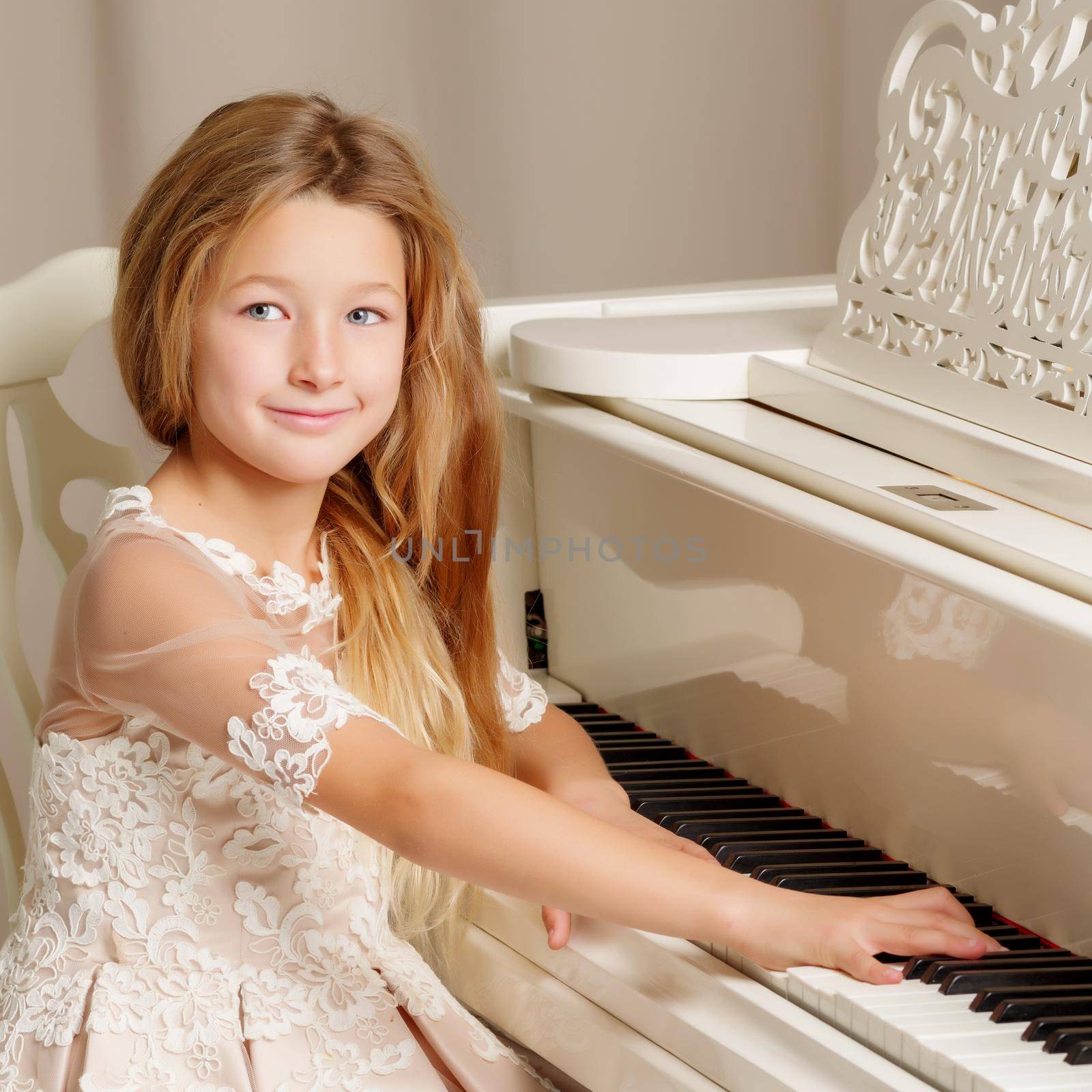 Beautiful little girl near a white grand piano. The concept of education and school, children's creativity.