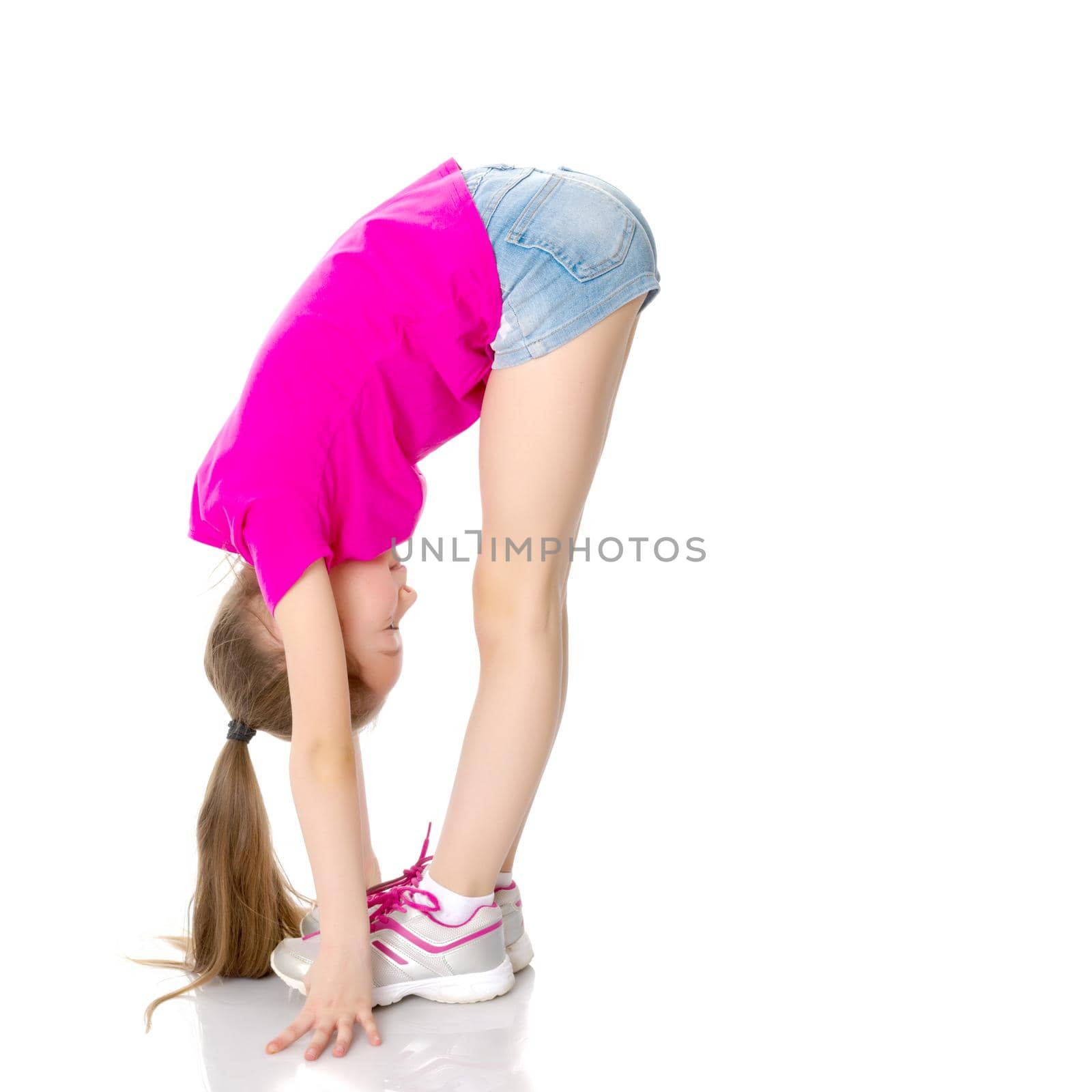 A sweet little girl shows gymnastic exercises that she learned at a sports school. The concept of sport and fitness. Isolated on white background.