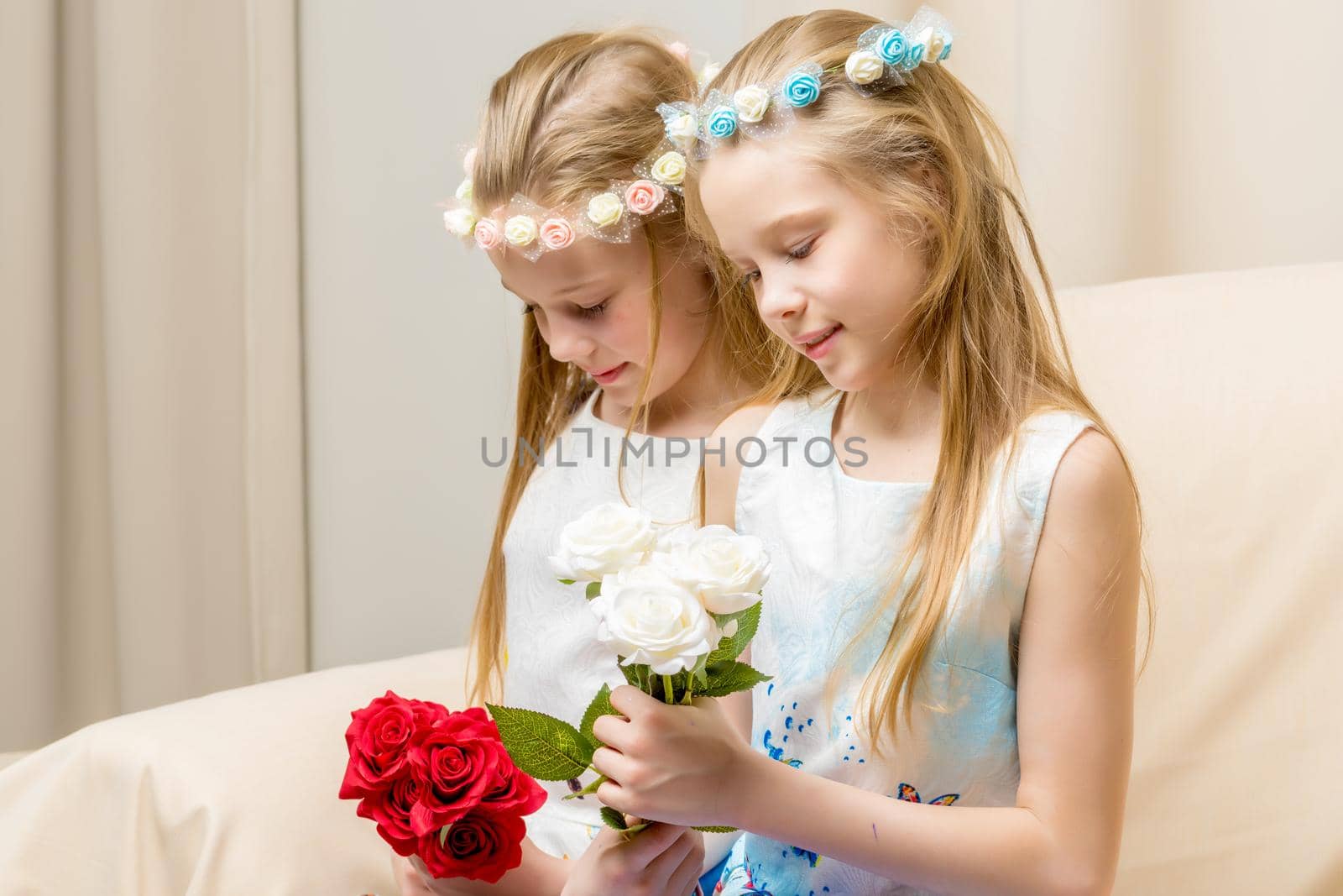 Two beautiful little girls with flowers in the studio. The concept of happy people, children.