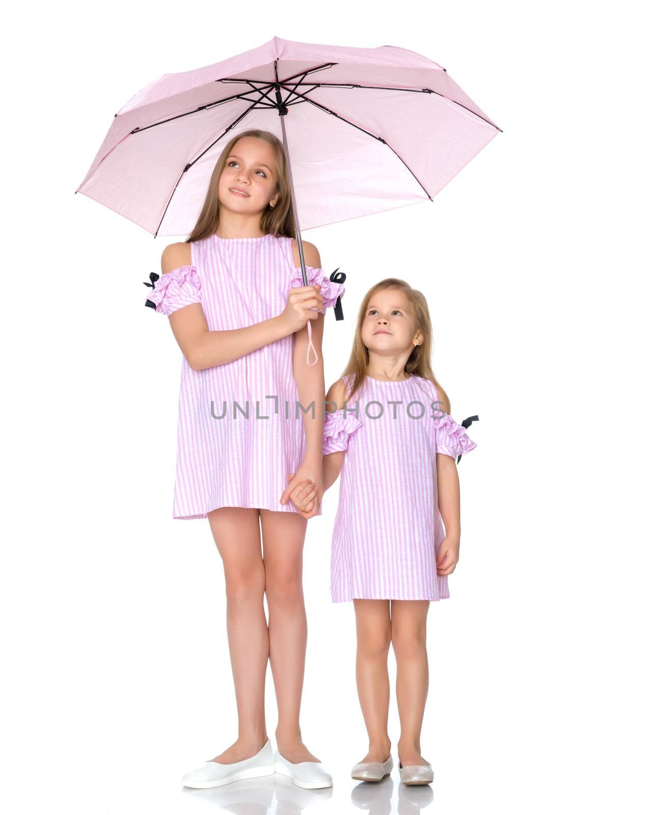 Lovely little girls hid under the umbrella. The concept of a happy childhood, family vacation. Isolated on white background.