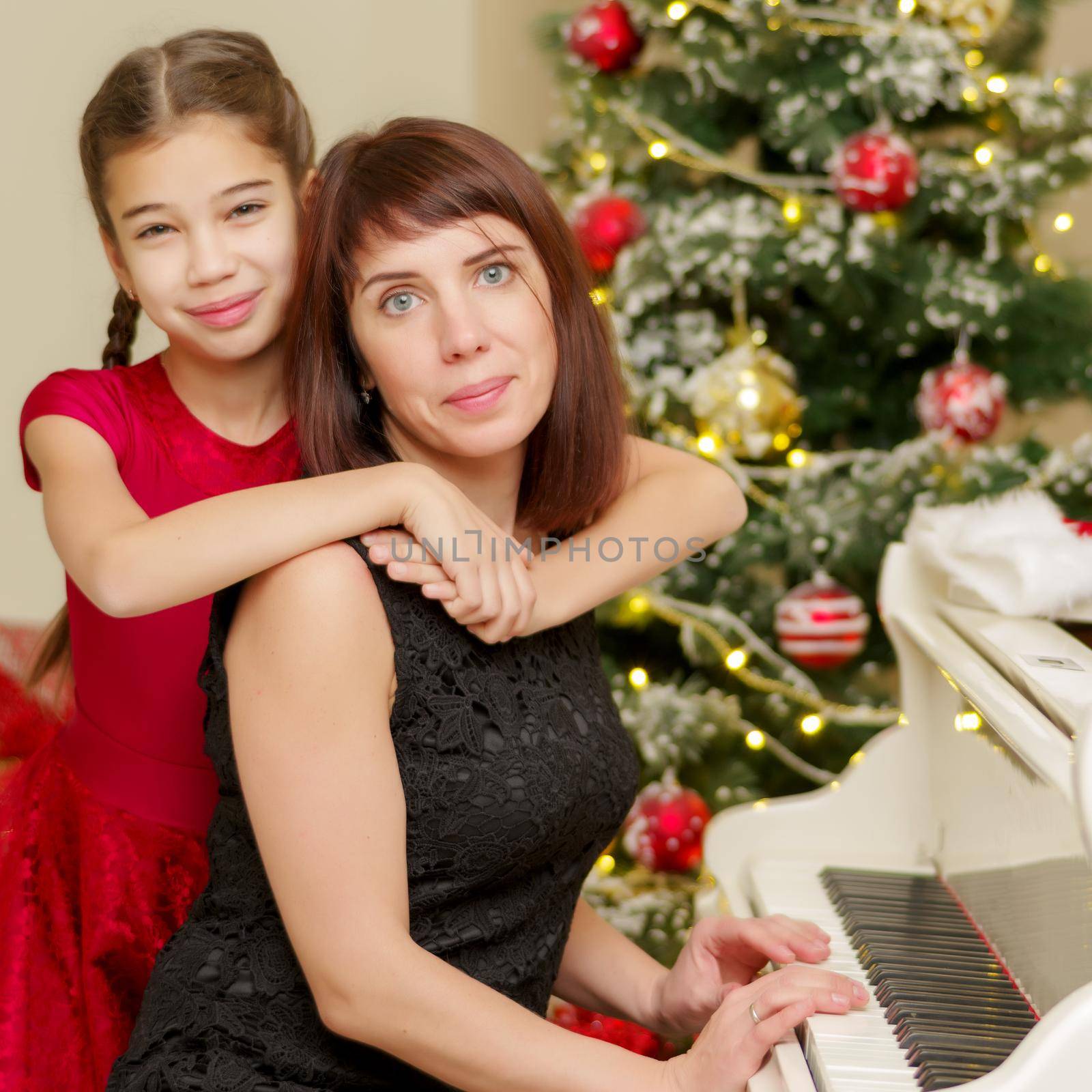 Mom and daughter in the new year near the white piano. by kolesnikov_studio