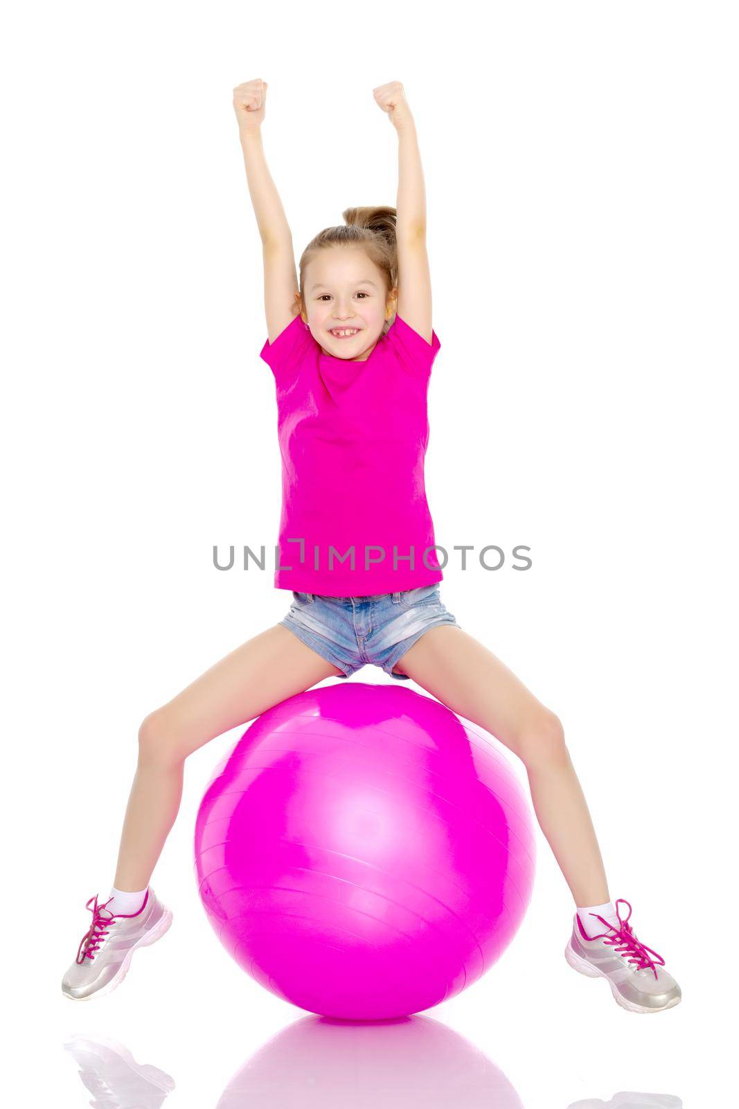 A little girl is jumping on a big ball for fitness. The concept of sport and a healthy lifestyle. Isolated on white background.