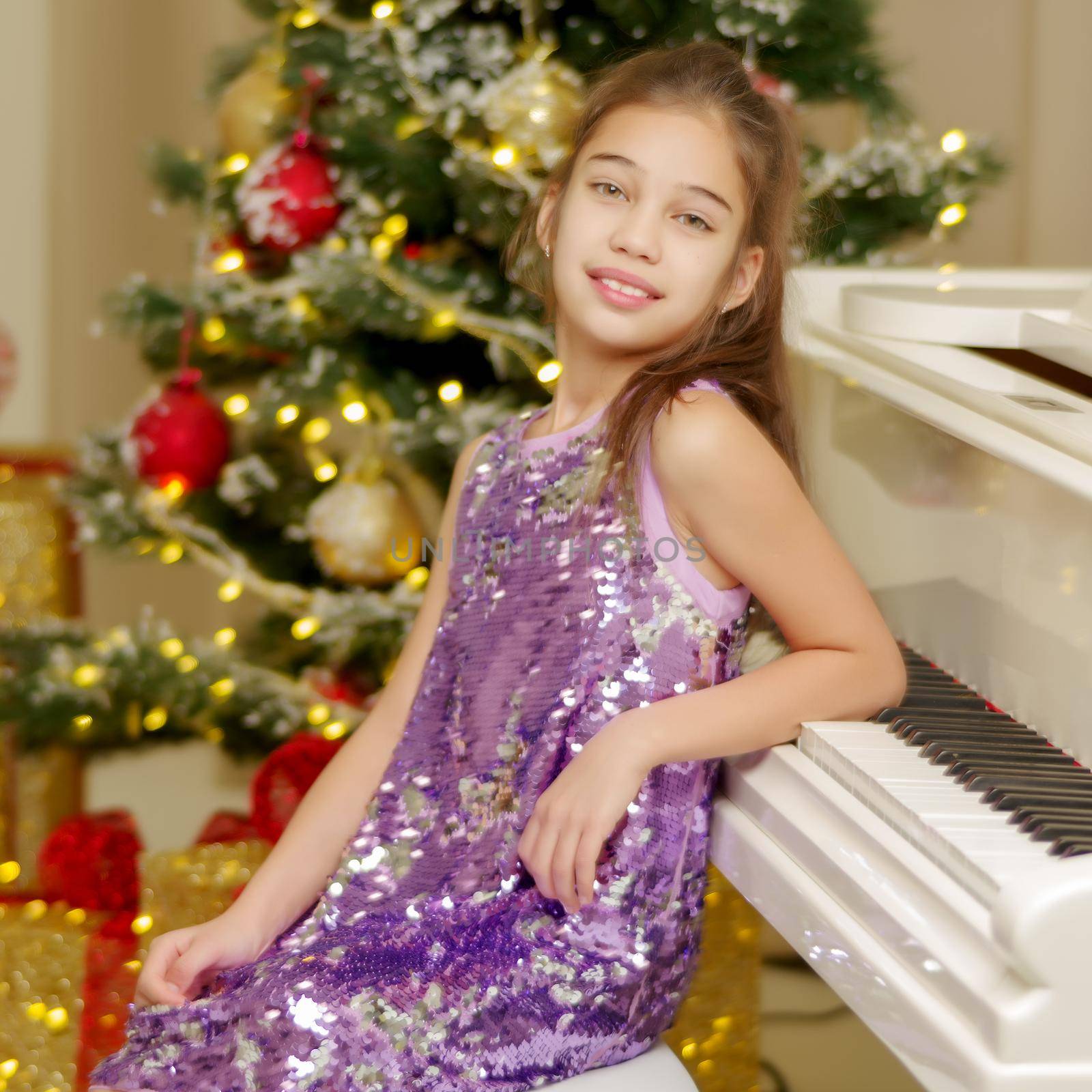 Little girl near the piano and Christmas tree. by kolesnikov_studio