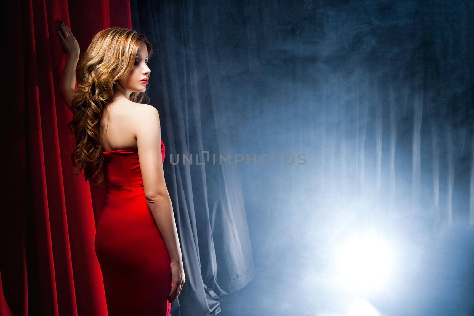 Portrait of a beautiful woman posing in a red dress in front of the scenes