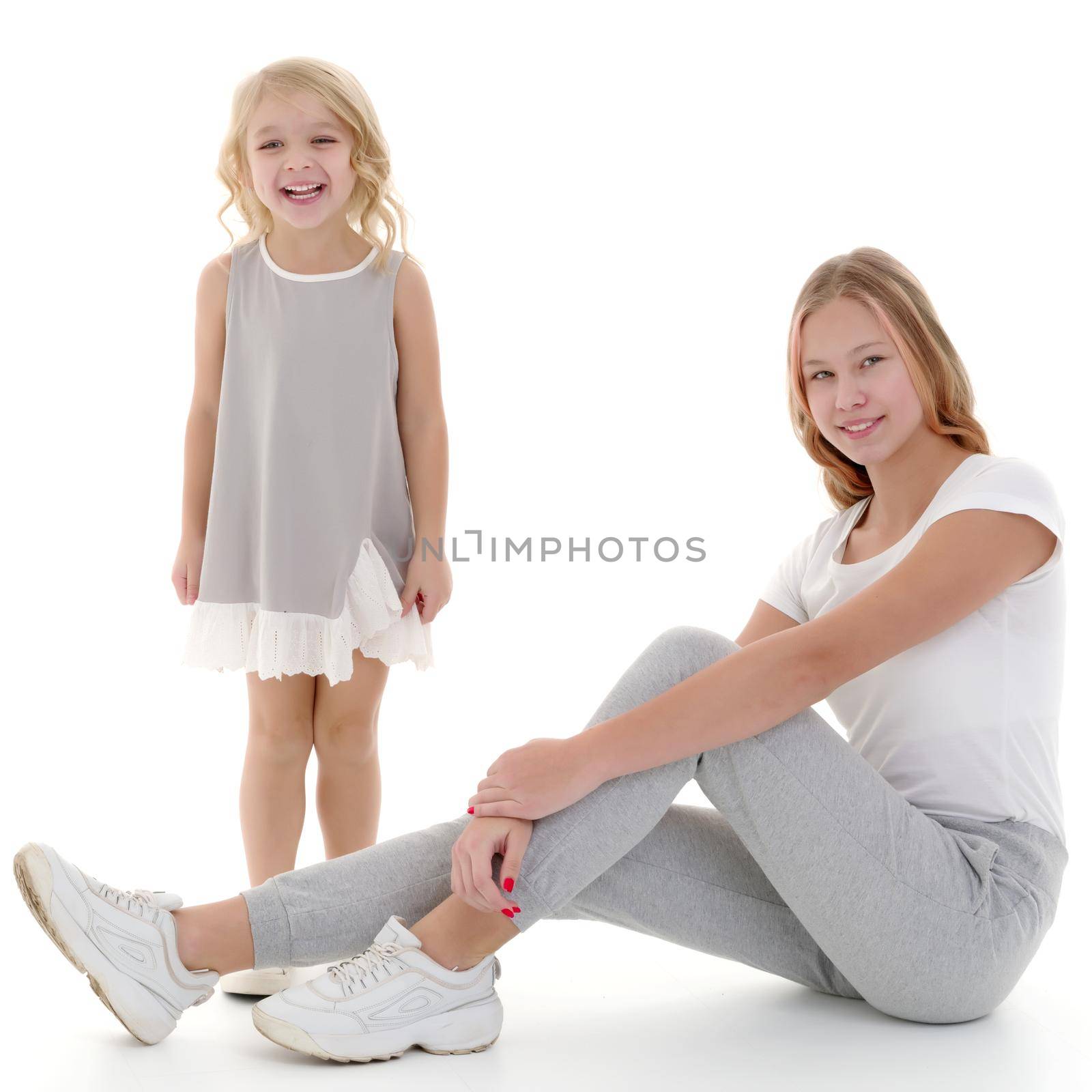 Two funny girls of different ages in the studio on a white background. The concept of a happy childhood. Isolated on white background.