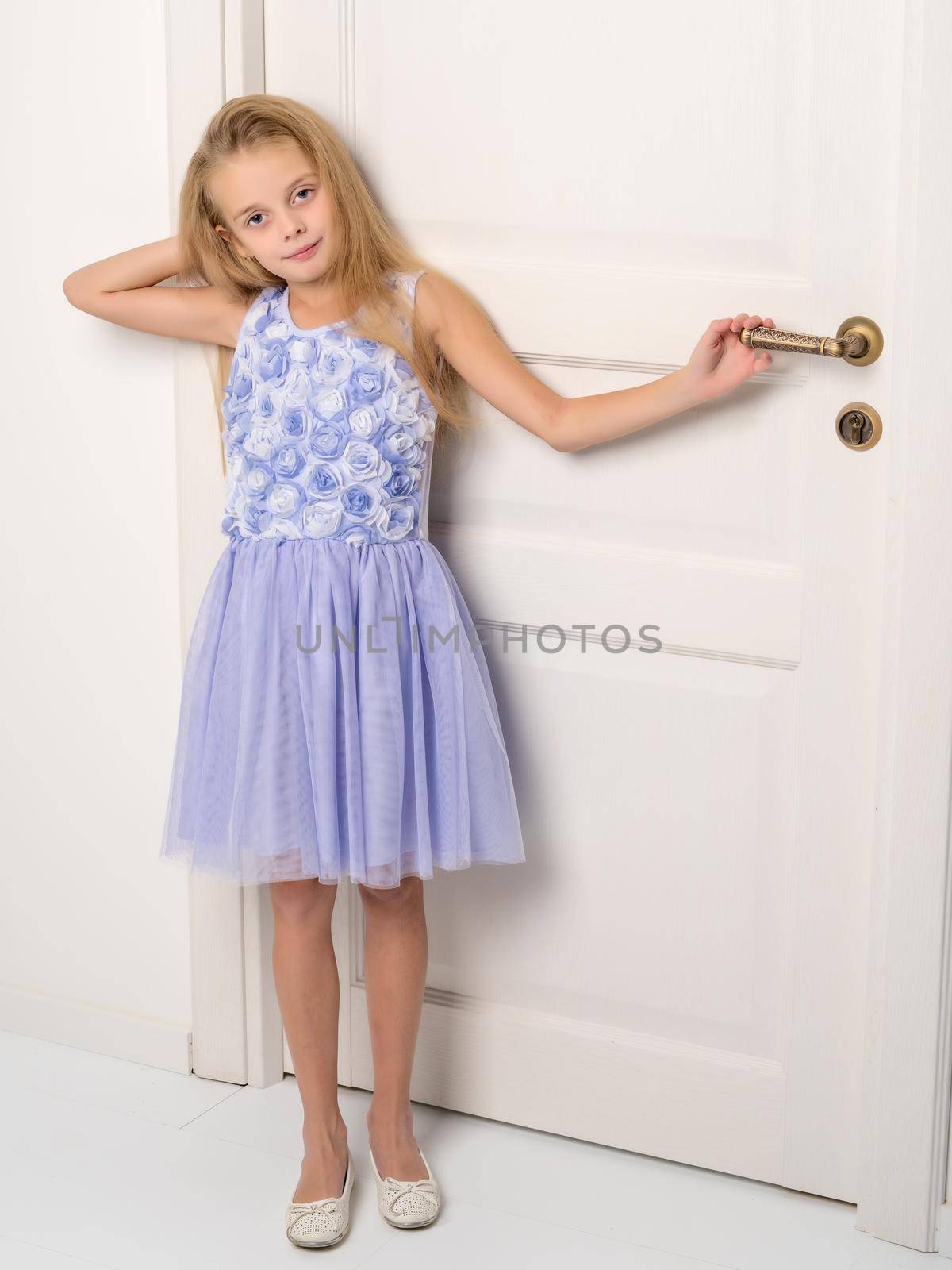 A nice little girl is standing by the door. The concept of family happiness and a home.