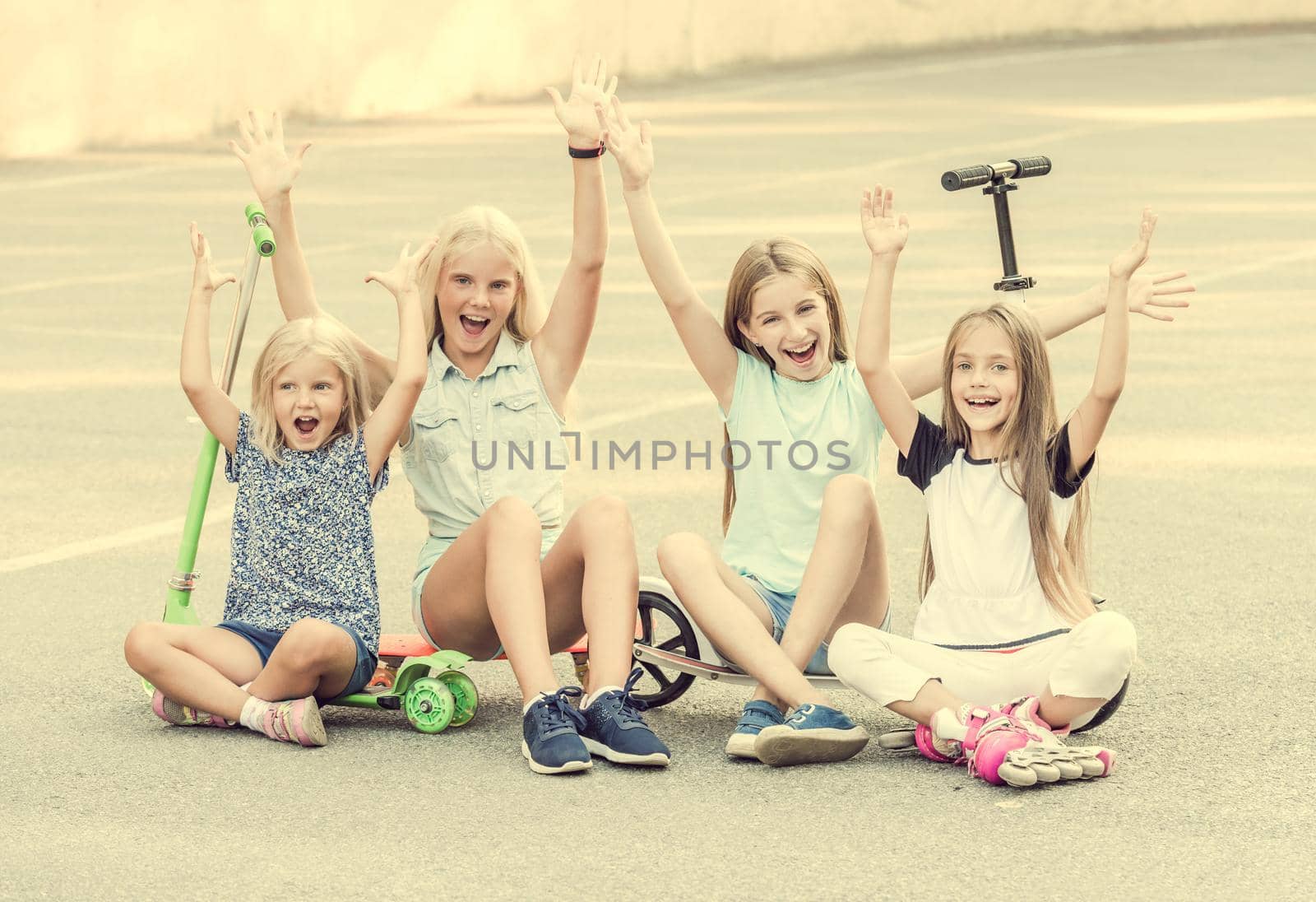 Pretty little girls smiling sitting on the ground with joyfully raised hands