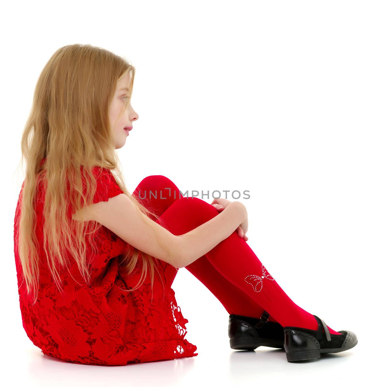 Cute girl posing on the floor in the studio. Hugs his knees. Isolated on white background. The concept of beauty and fashion