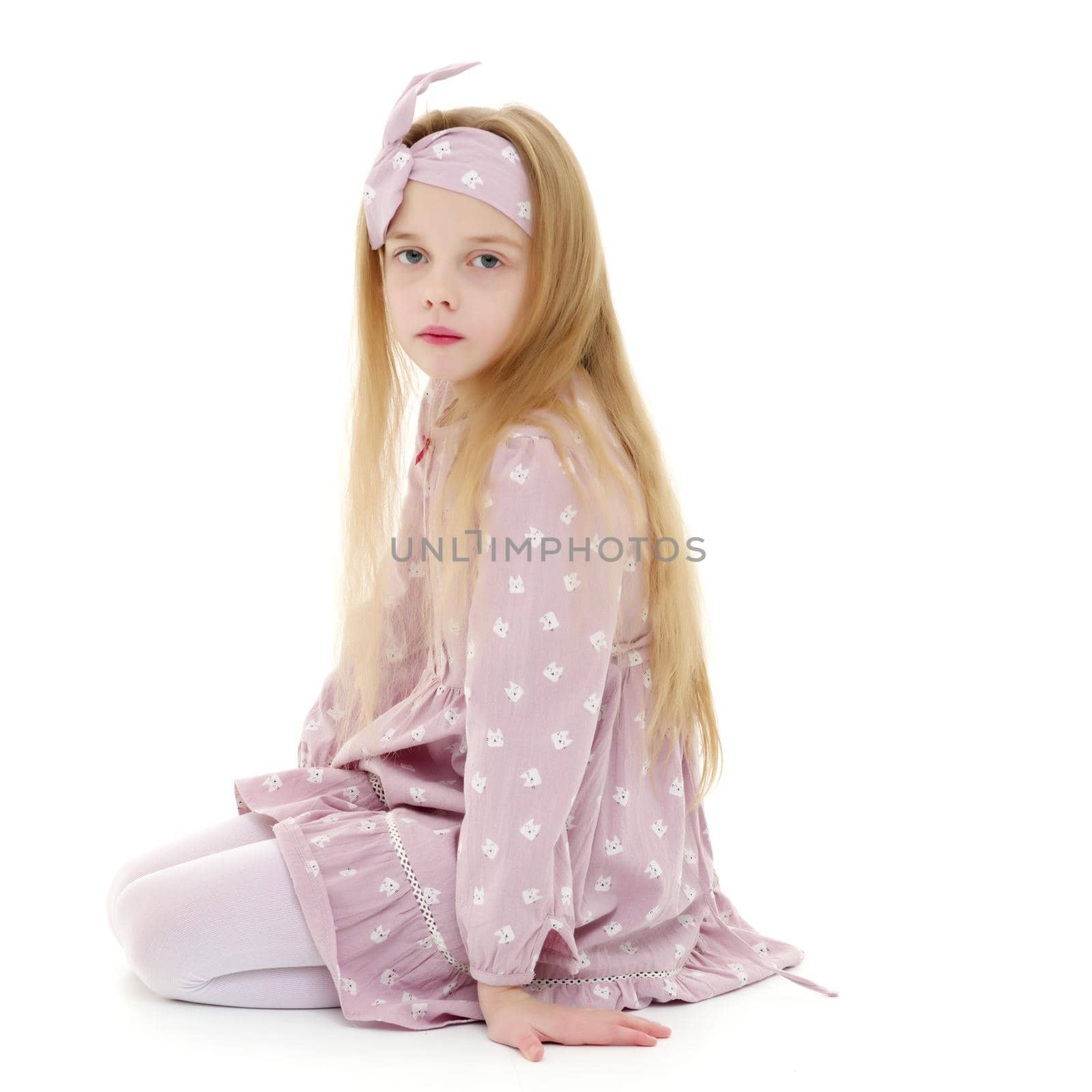 Beautiful little girl kneels in the studio on a white background. The concept of beauty and fashion, children's emotions. Isolated.