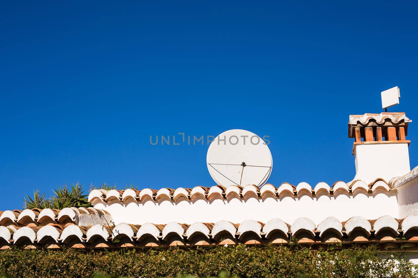 satellite dish and TV antennas on the house roof with blue sky background