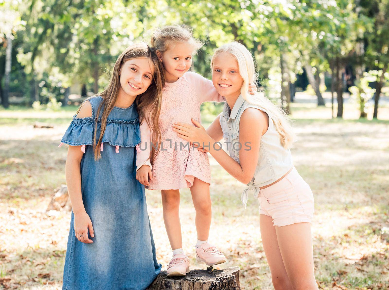Pretty smiling little girls stand hugging in a sunshine autumn park