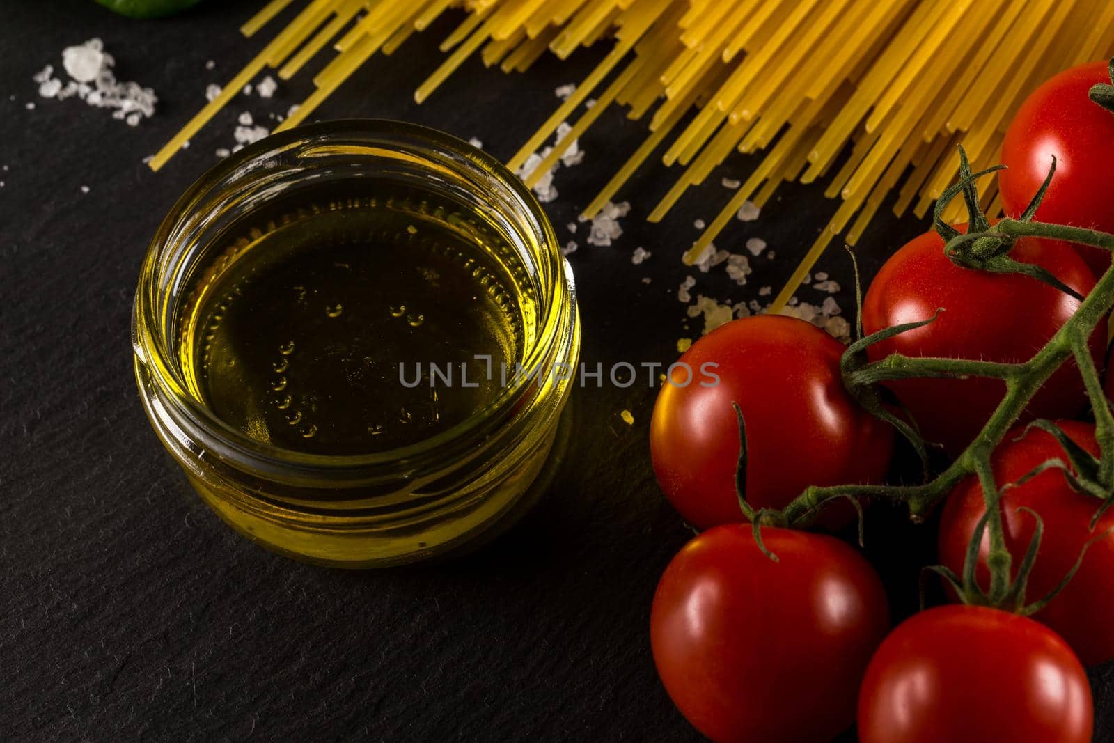 Food frame photo. Pasta ingredients. Cherry-tomatoes, spaghetti pasta, garlic, basil, salt  on dark grunge backdrop, copy space, top view, horizontal