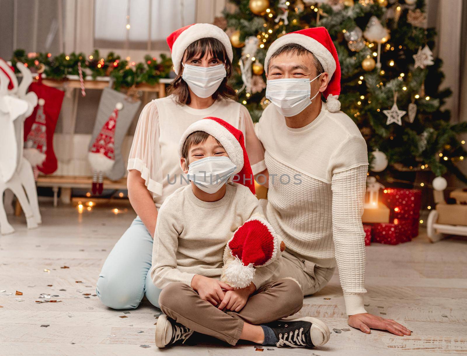 Happy family in protective masks celebrating christmas at home during coronavirus pandemic