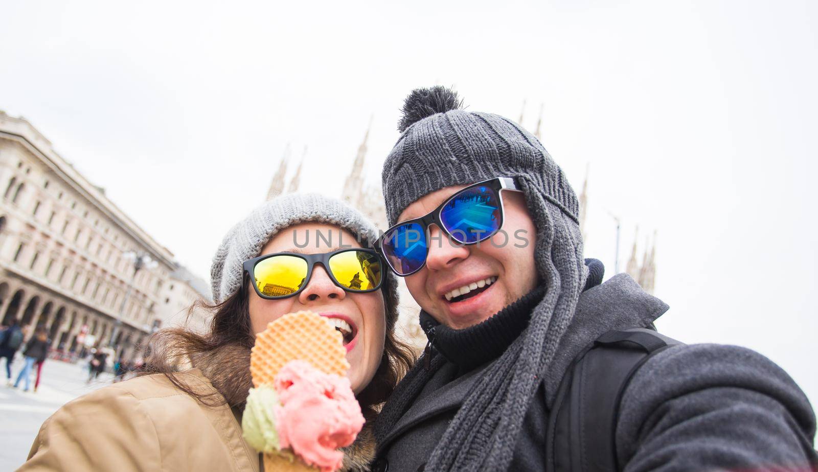 Travel in winter and Italy concept - Happy young couple take selfie photo with ice-cream in front of Milan Duomo Cathedral