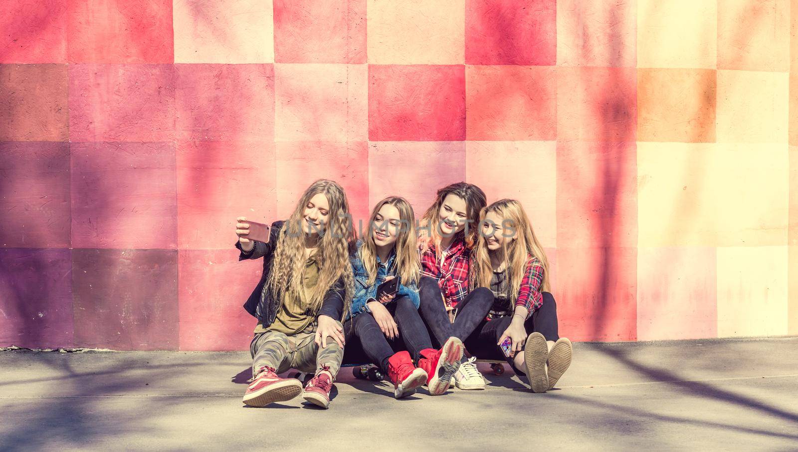 Teenage girls making selfie outdoors while sitting on longboards. Happy friends in the park on a sunny day. Happy friendship concept