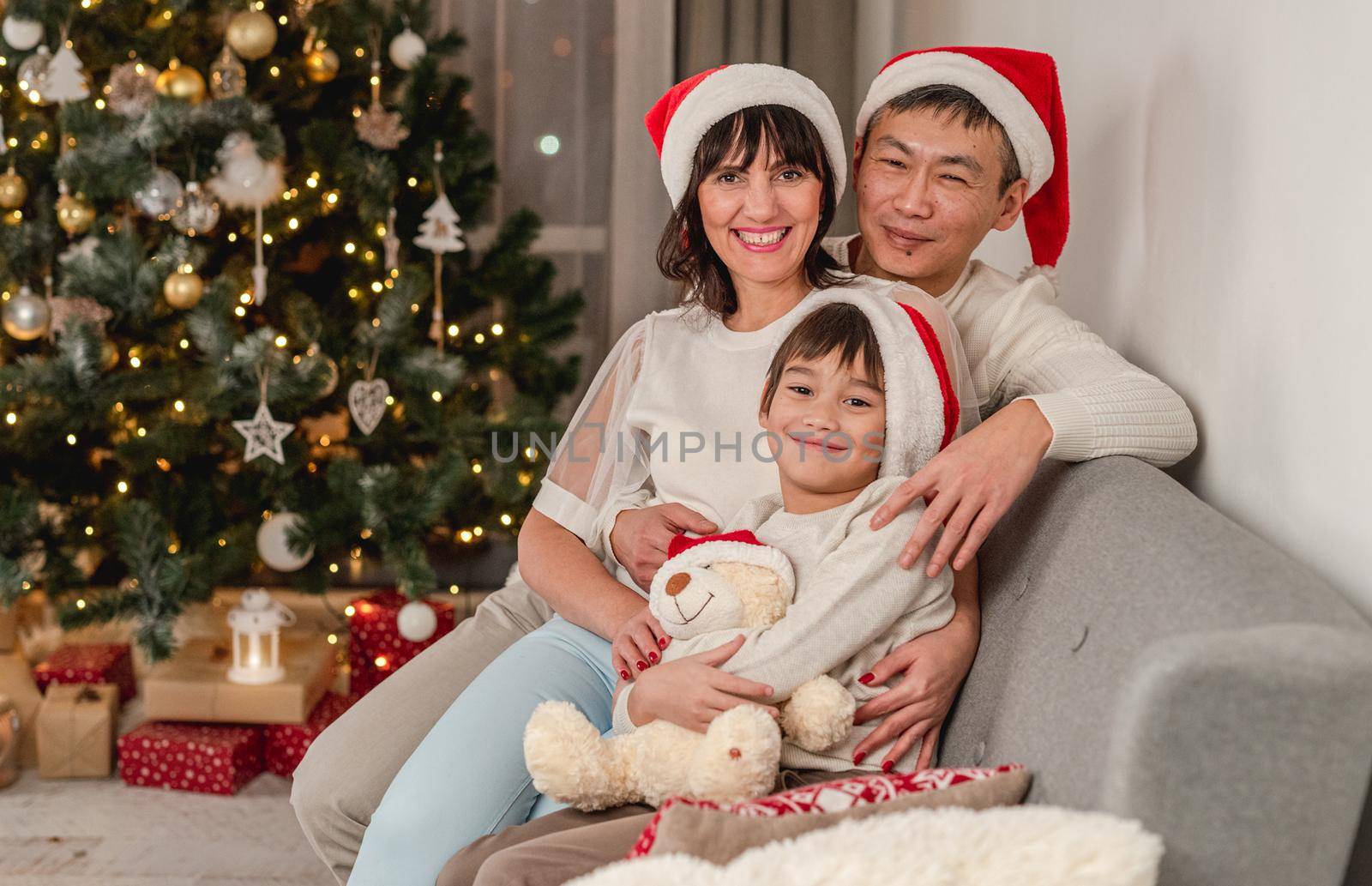 Happy family next to christmas tree by tan4ikk1