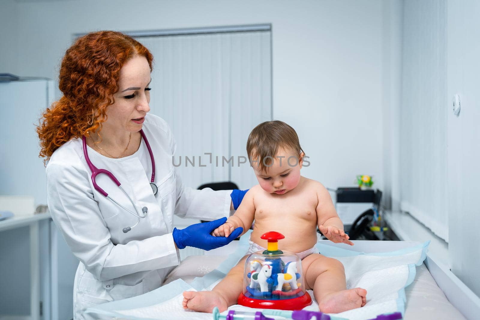 Pediatrician doctor concept. Children medical care. One year old baby girl examined by female pediatrician in clinic office. Child visiting doctor for health check-up. Doctor examine little patient.