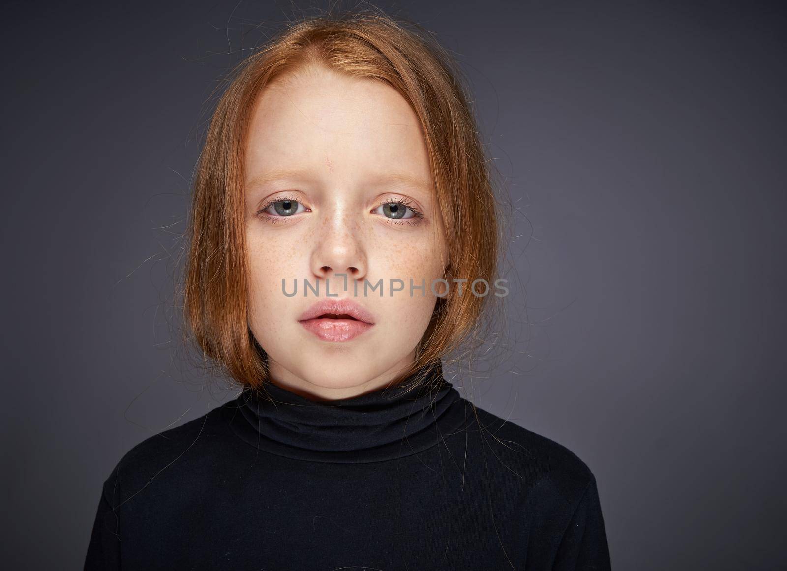 red-haired girl with freckles on her face in a black sweater posing. High quality photo