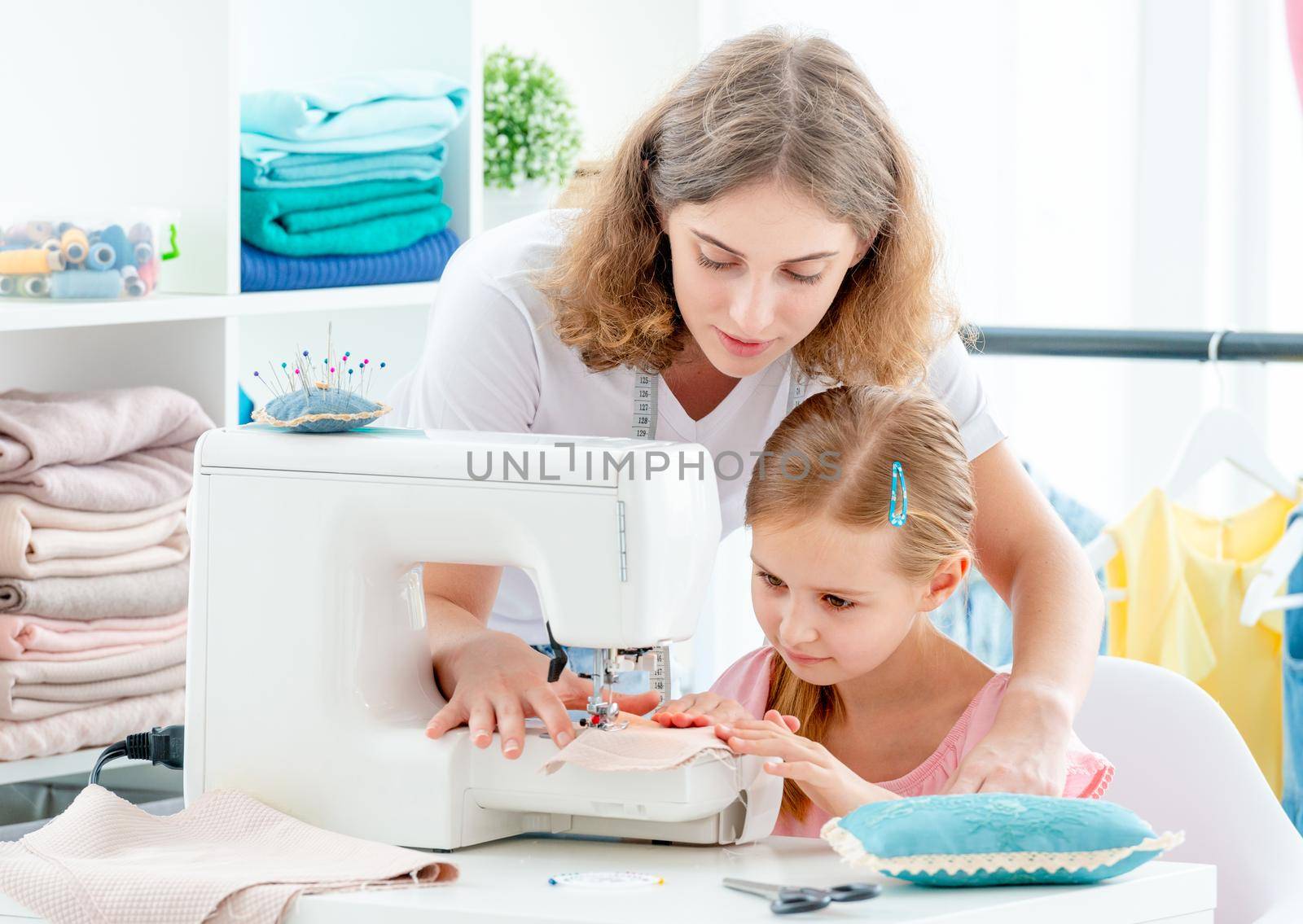 Mother and daughter are sewing on sewing machine at home
