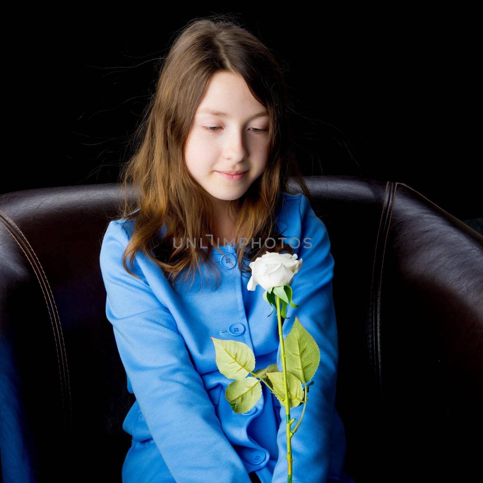 Beautiful little girl with a flower in her hand. The concept of style and fashion. On a black background.