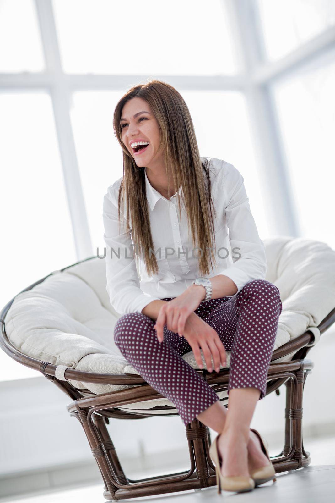 laughing young woman sitting in comfortable chair by asdf