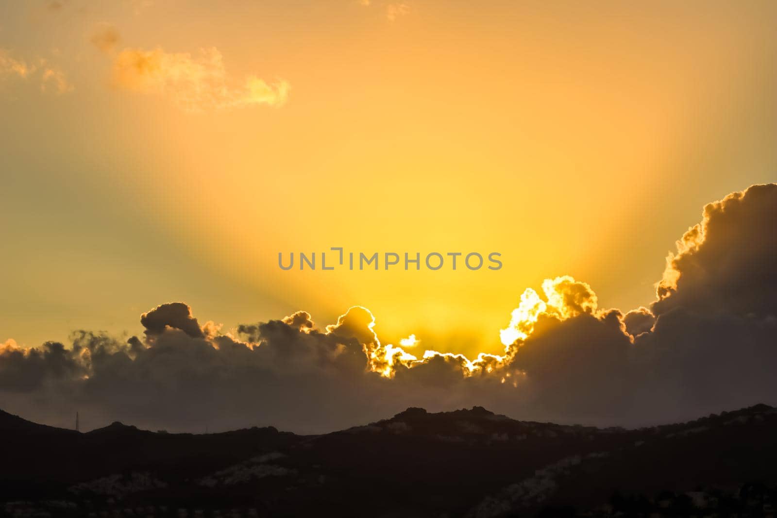 Background from a beautiful sunset with clouds and sunlights over mountanous coast. High quality photo