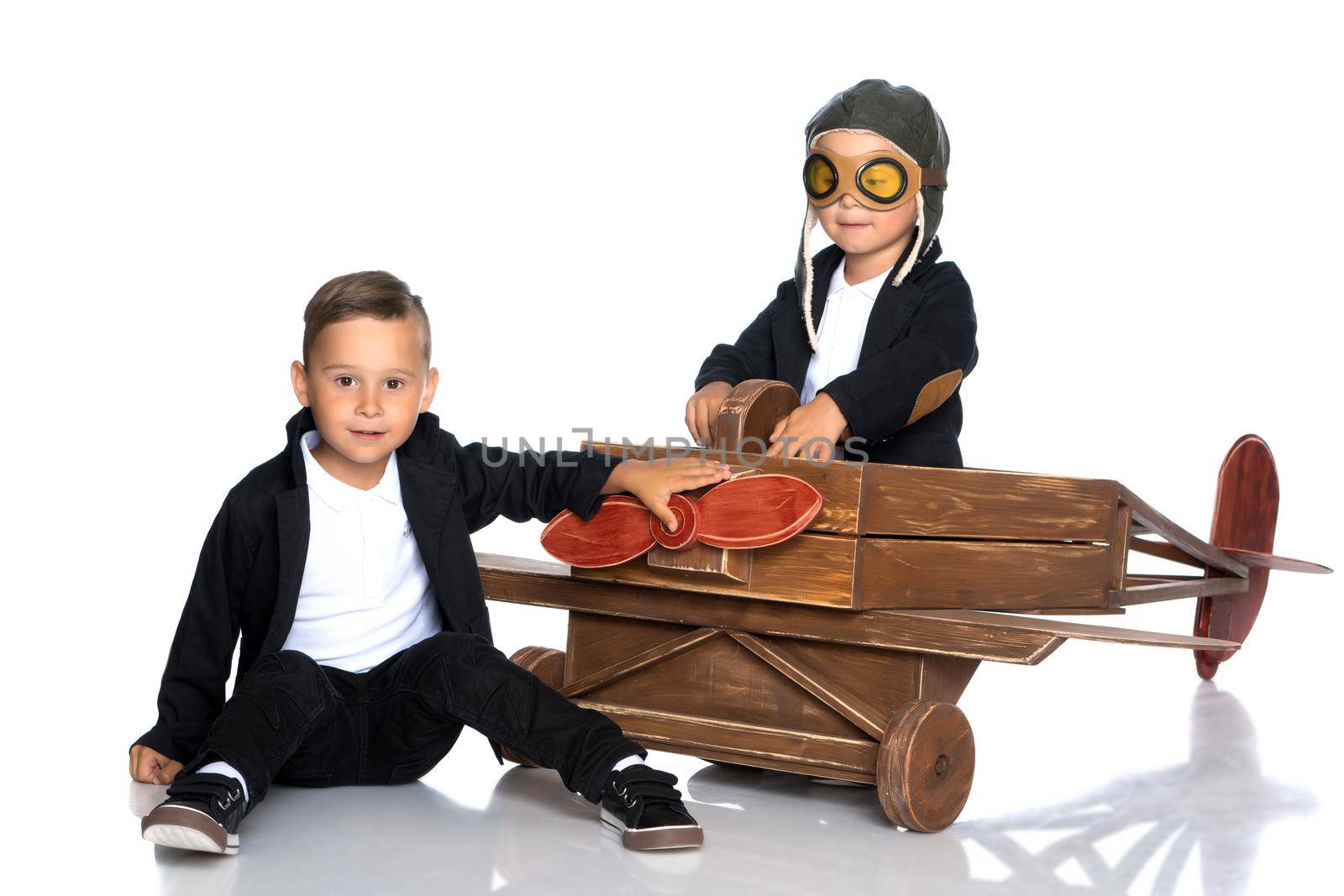 Two cute little boys are playing with a toy airplane. Isolated on white background.