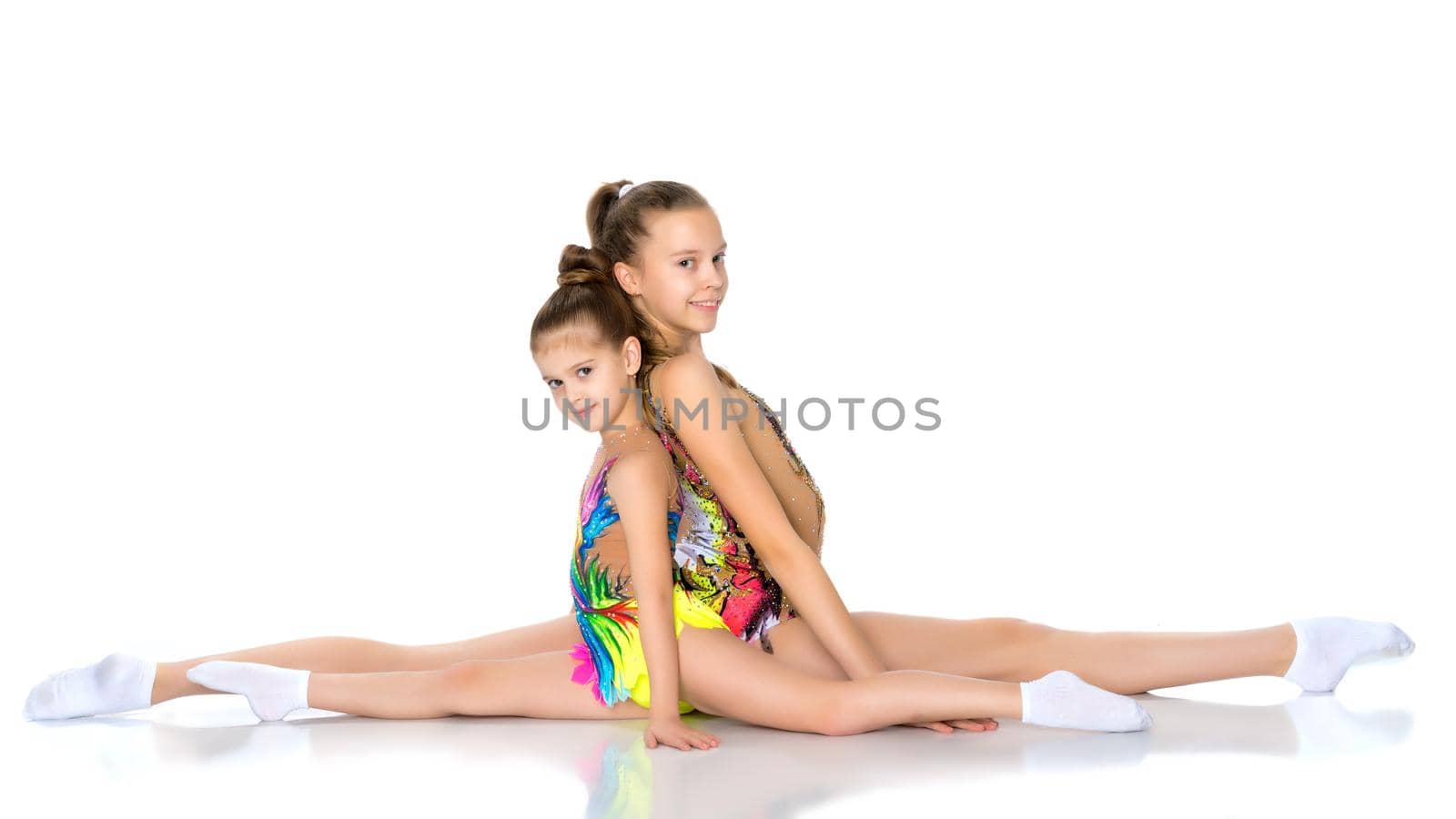 Lovely girls gymnasts together make a twine. The concept of sport, fitness, healthy lifestyle. Isolated on white background.