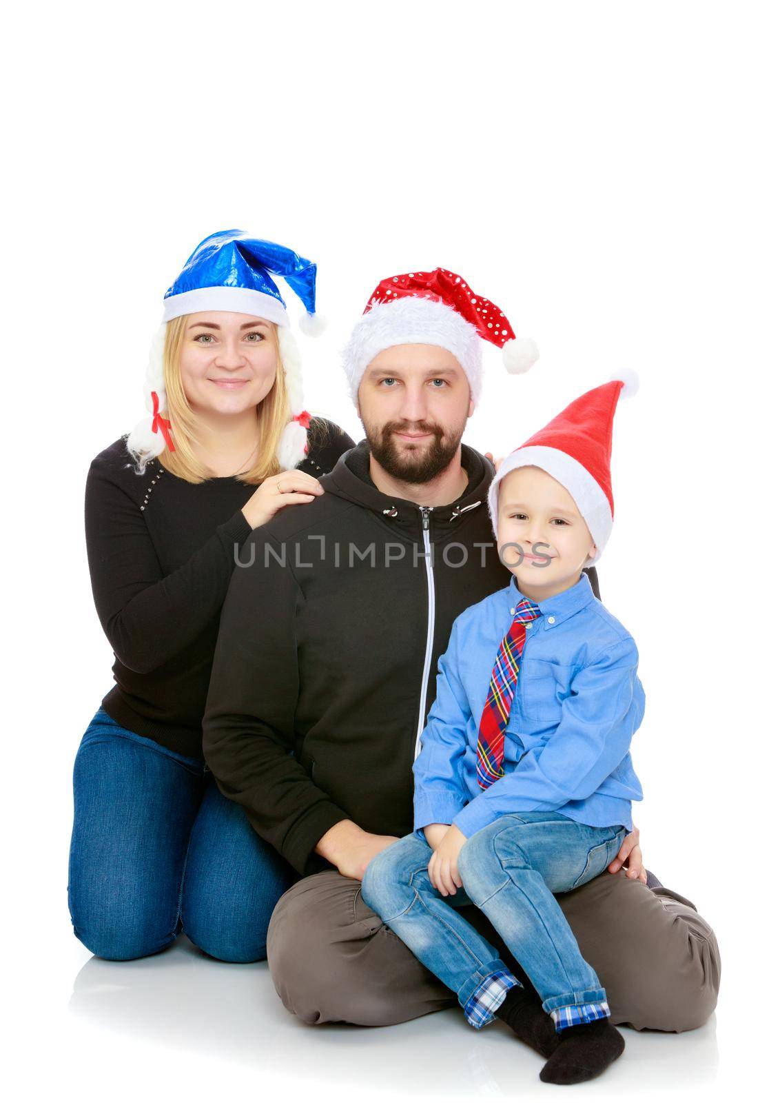 Happy family of 3 people in caps of Santa Claus, the Christmas tree and the fireplace in the Christmas night.Isolated on white background.