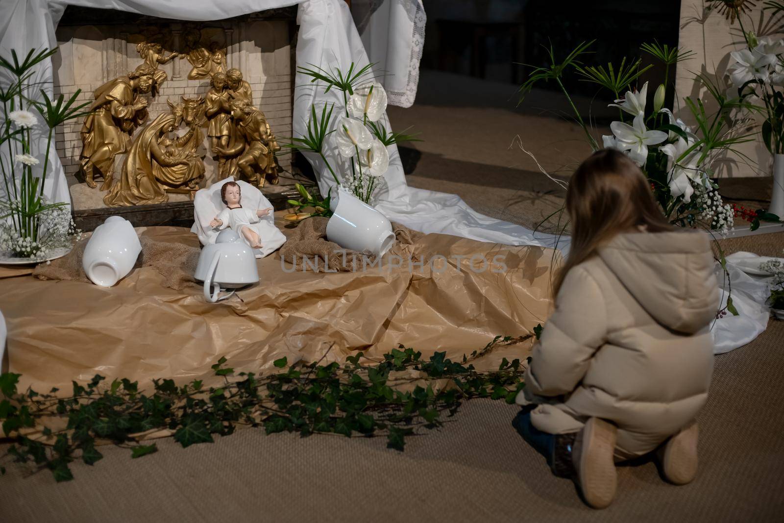 A girl looks at christmas creche with Joseph Mary and small Jesus