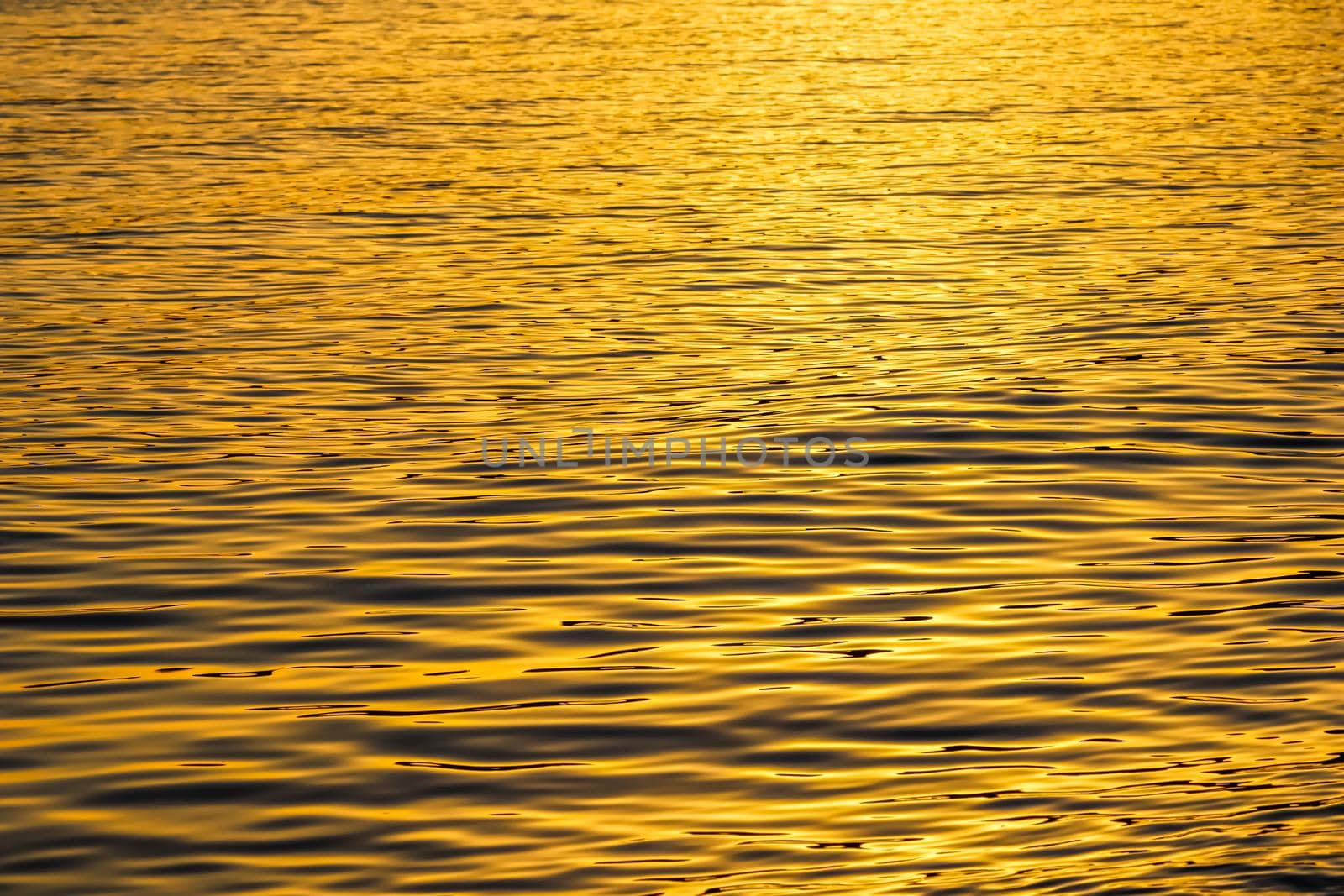 Golden sea waves in sunset glow as surface background. Summer holidays and coastal nature concept